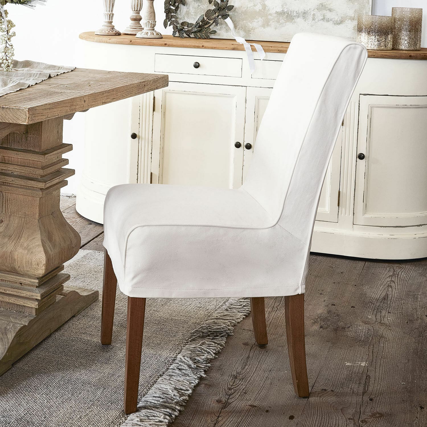 Chaise avec housse Mankato Chaise rembourrée blanche avec pieds en bois près d'une table rustique en bois dans une salle à manger