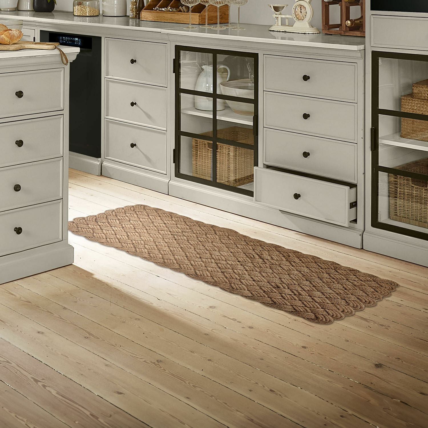 Tapis long Hildas Tapis marron tressé sur un sol en bois clair dans une cuisine avec des armoires grises