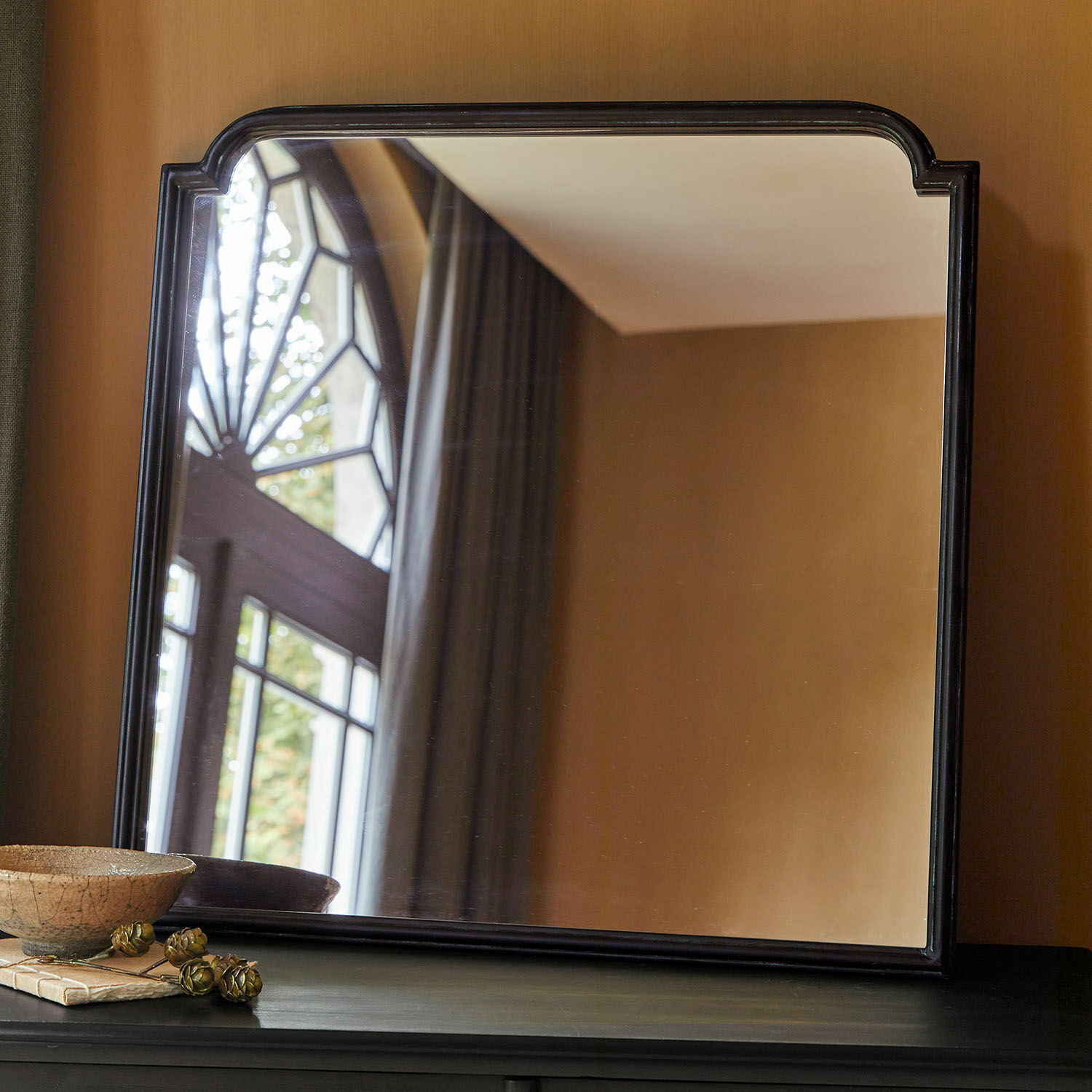 Miroir Miravois Miroir à cadre noir aux coins arrondis posé sur un meuble sombre dans un intérieur classique