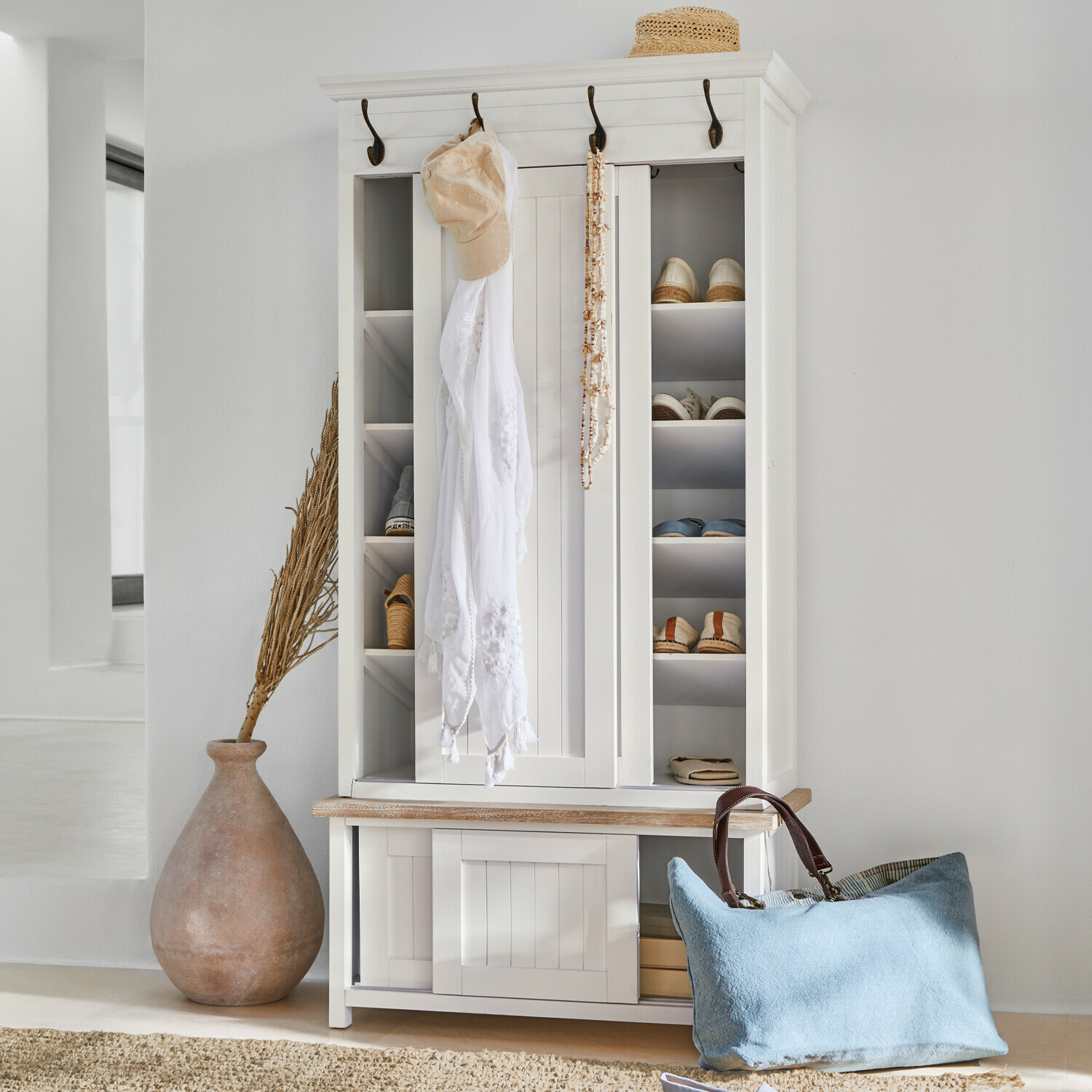 Armoire à chaussures en bois blanc avec crochets, étagères, sac bleu et chapeau en paille