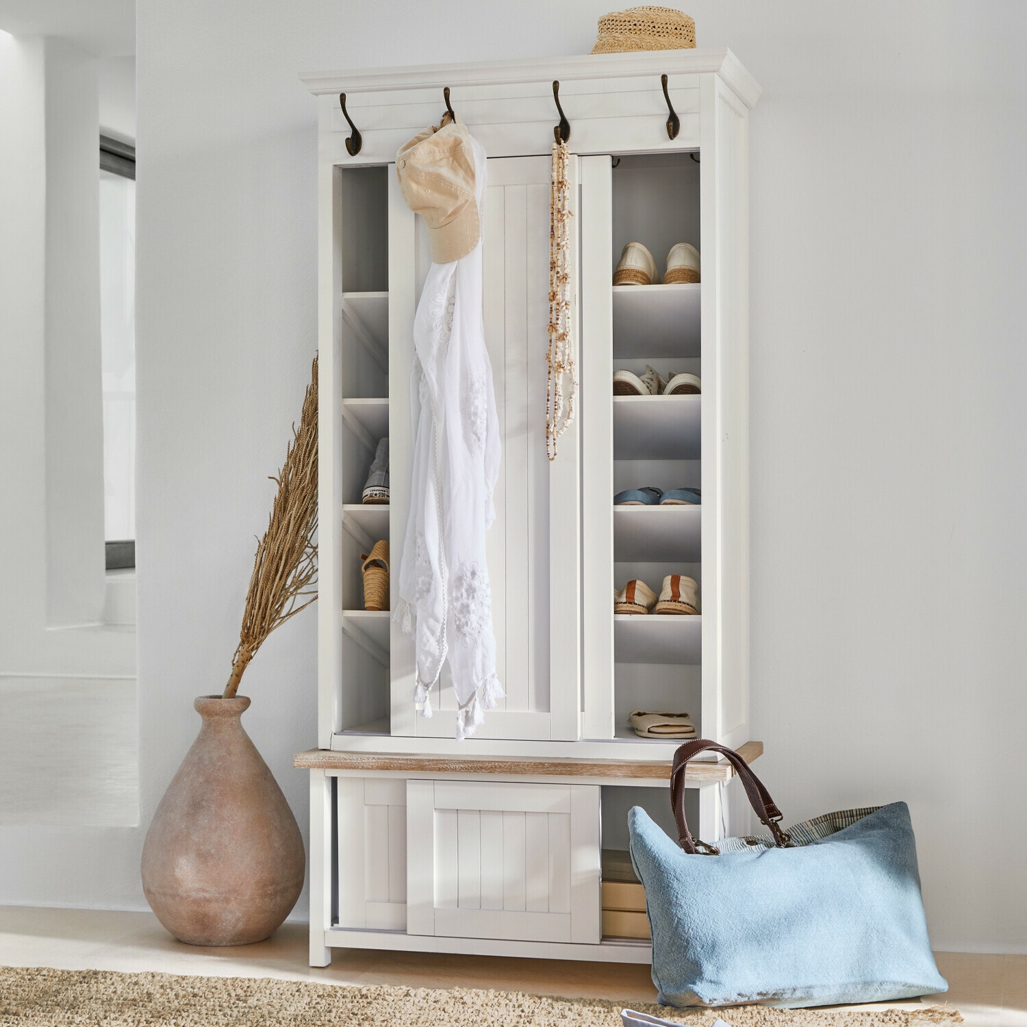 Meuble d’entrée Remerton Armoire à chaussures en bois blanc avec crochets, étagères, sac bleu et chapeau en paille