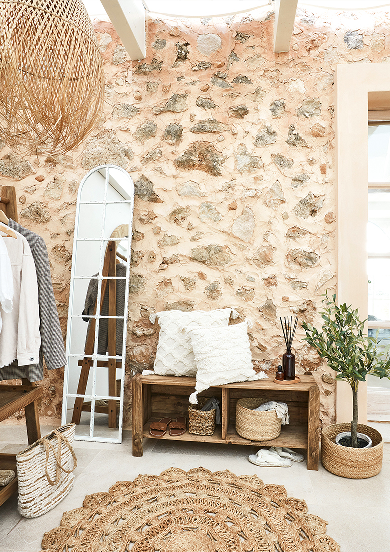 Coin chaleureux avec banc en bois, coussins blancs et tapis en jute naturel style bohème