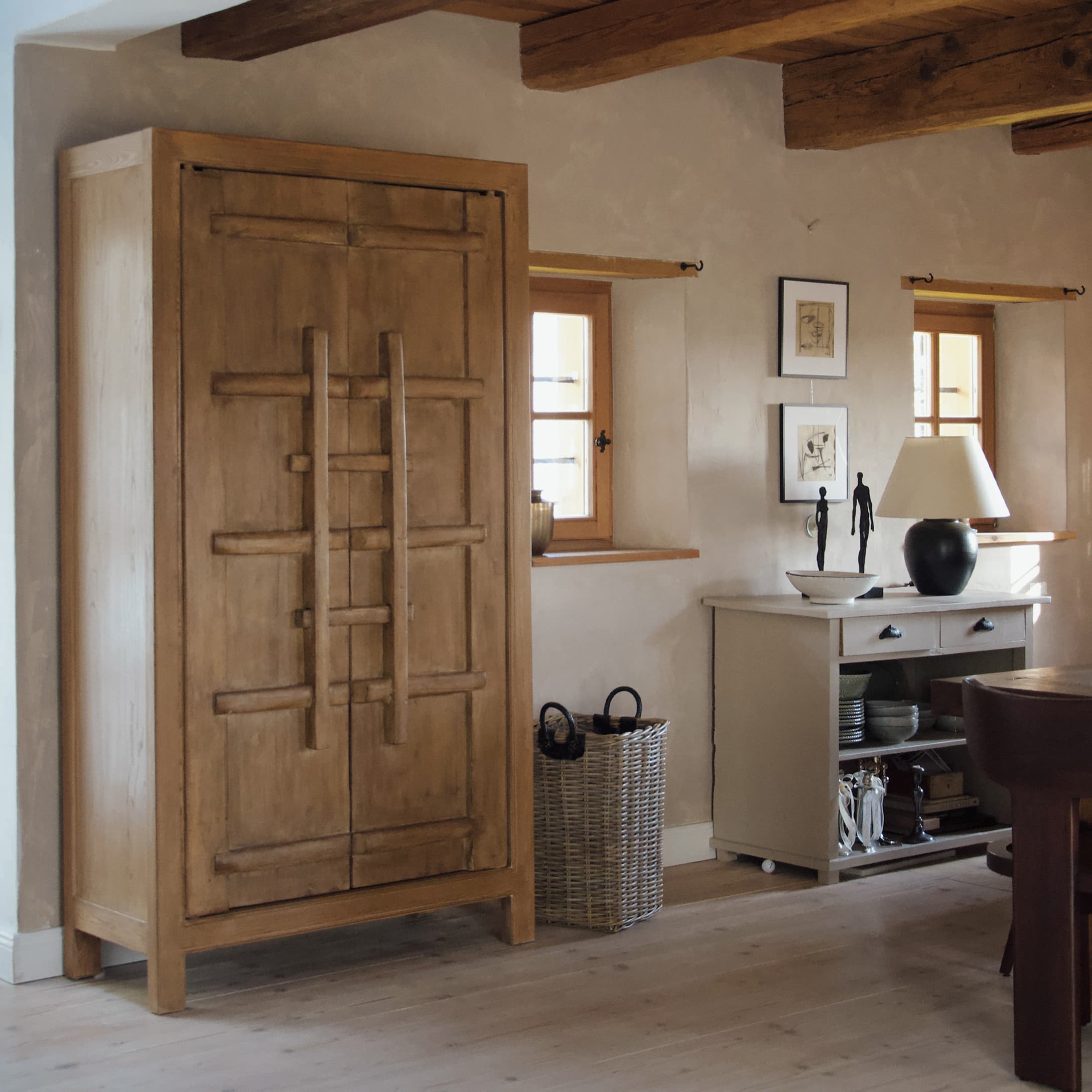 Armoire en bois naturel dans un intérieur rustique avec panier décoratif et commode blanche