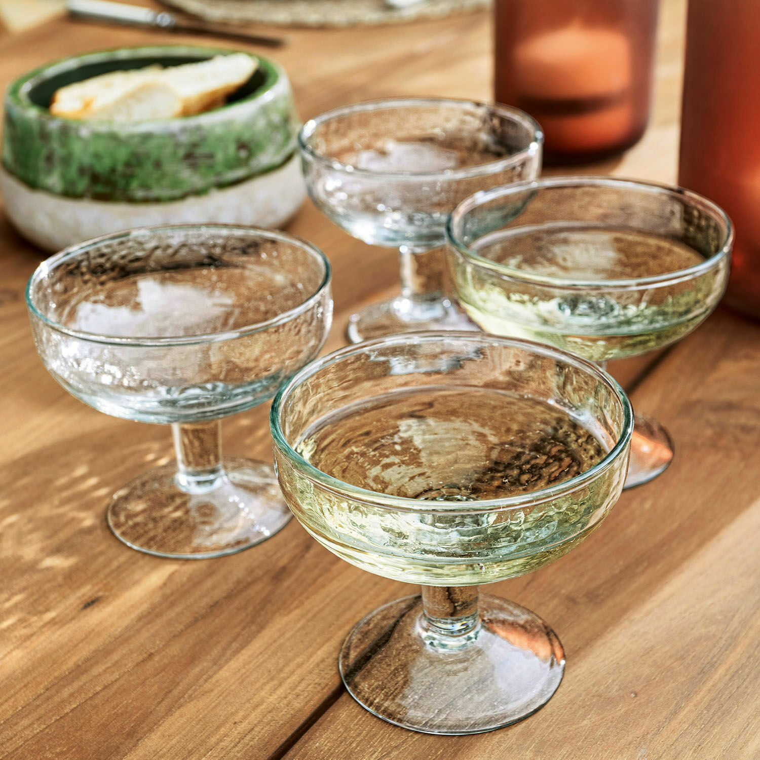Lot de 4 verres Port Vila Ensemble de quatre coupes à champagne en verre texturé transparent sur une table en bois