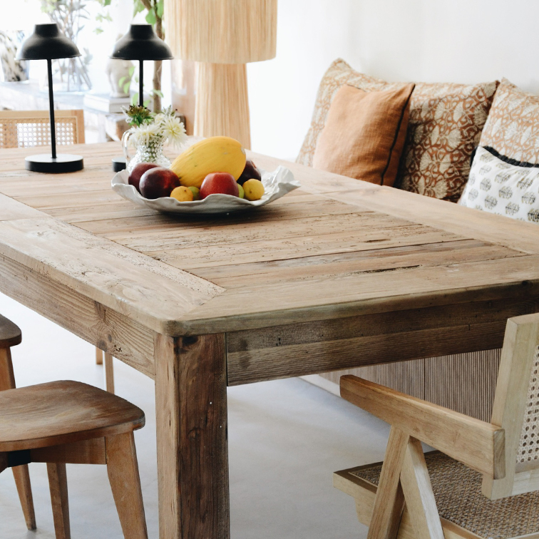 Table à manger rustique en bois avec bol de fruits et lampes sur un fond intérieur lumineux