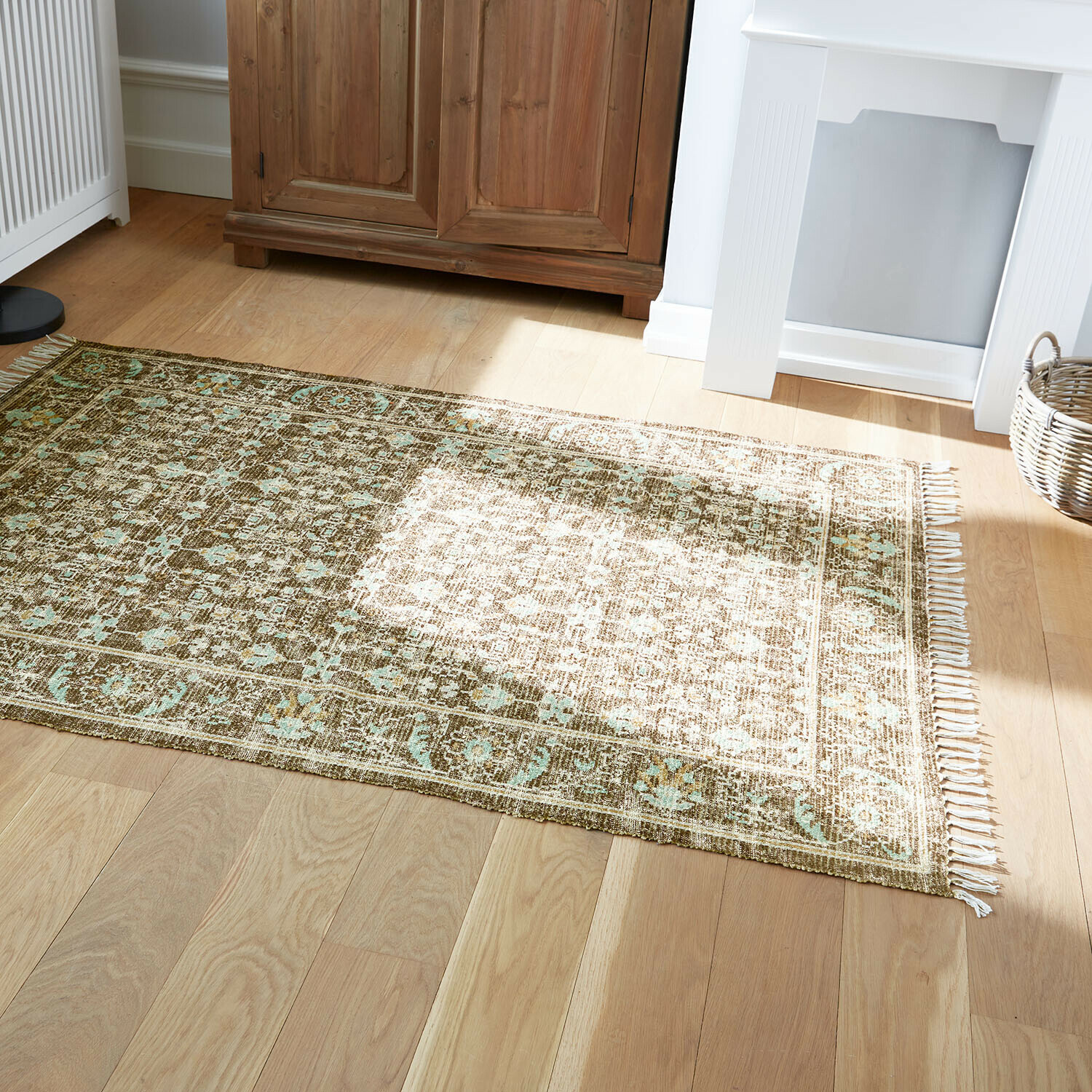 Tapis à motif vert et beige sur parquet en bois clair dans une pièce lumineuse