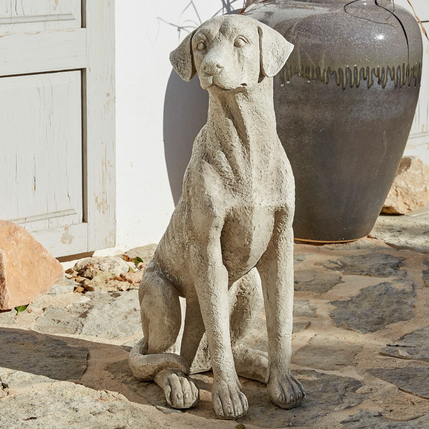 Chien décoratif Elliot Statue décorative de chien en béton gris posée sur un sol en pierre pour jardin