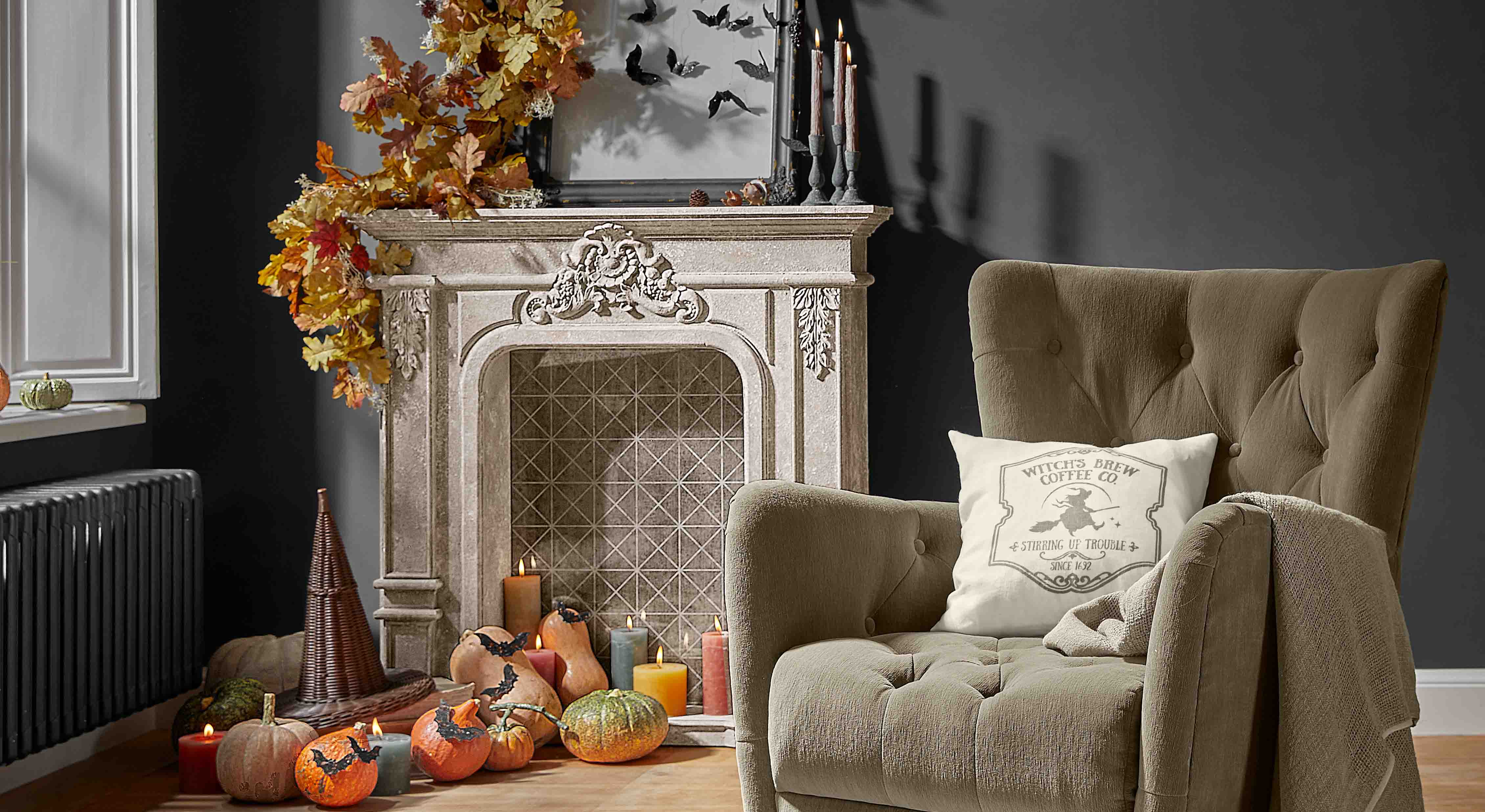 Cheminée décorative avec feuilles d'automne, citrouilles et bougies dans un salon cosy avec fauteuil beige