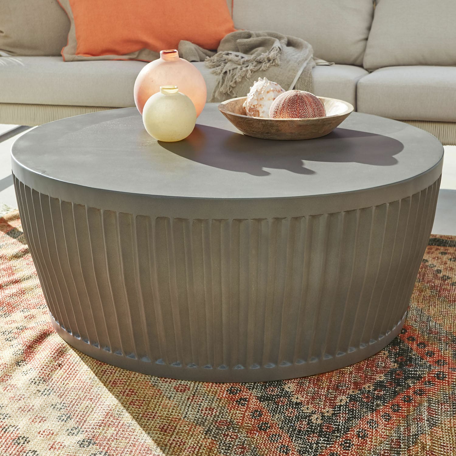 Table basse Vesalune Table basse ronde en métal gris avec base cannelée sur tapis coloré dans un salon lumineux