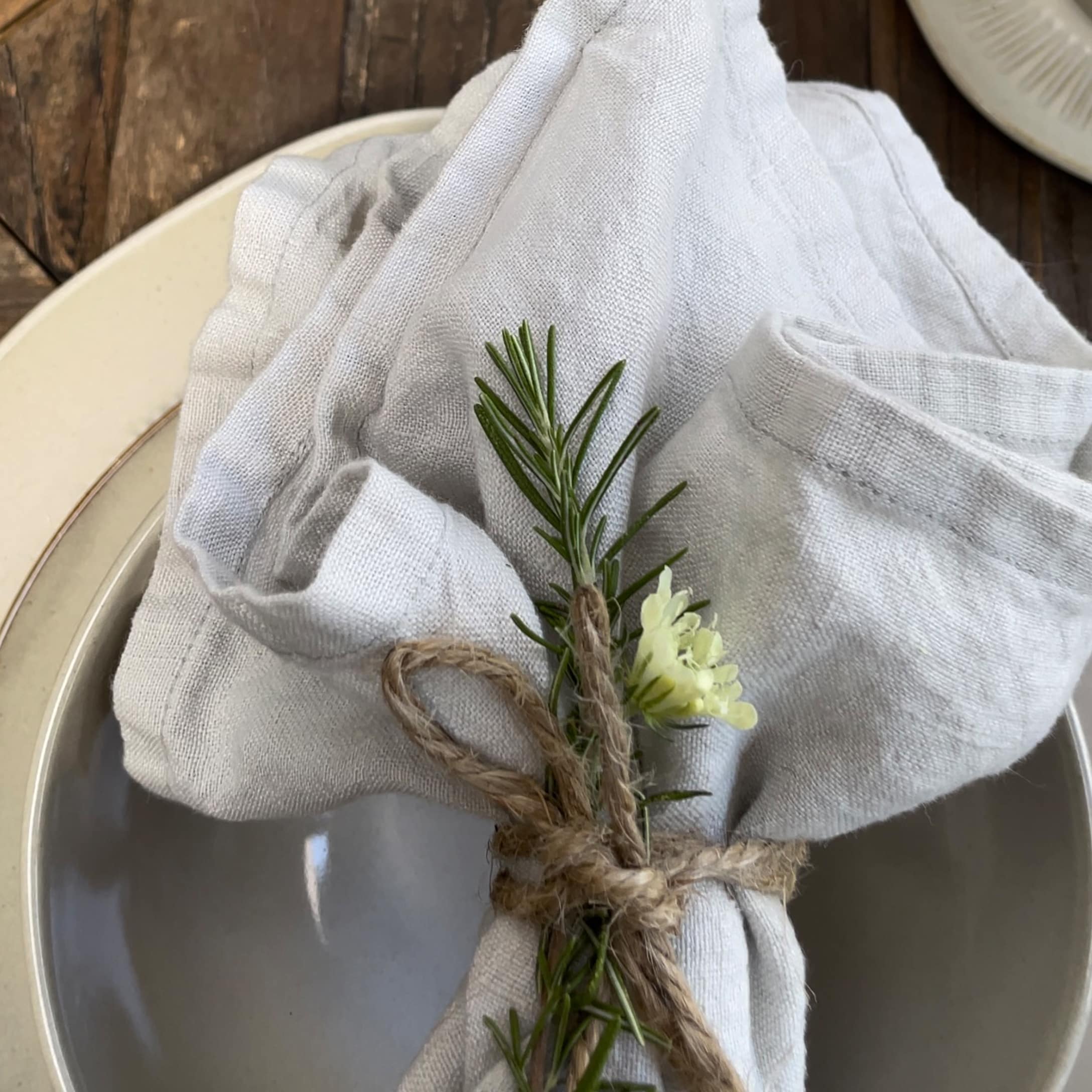 Nappe en lin blanc avec décoration de branche de romarin et fleur sur assiette en céramique
