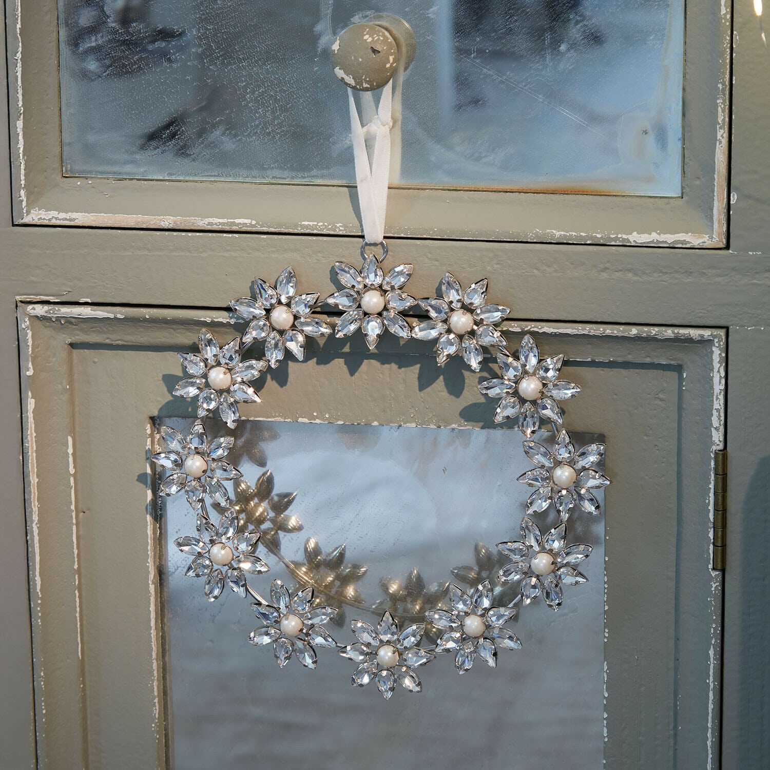 Couronne Torvynn Couronne décorative en cristal et perles suspendue à une porte grise, décoration intérieure élégante