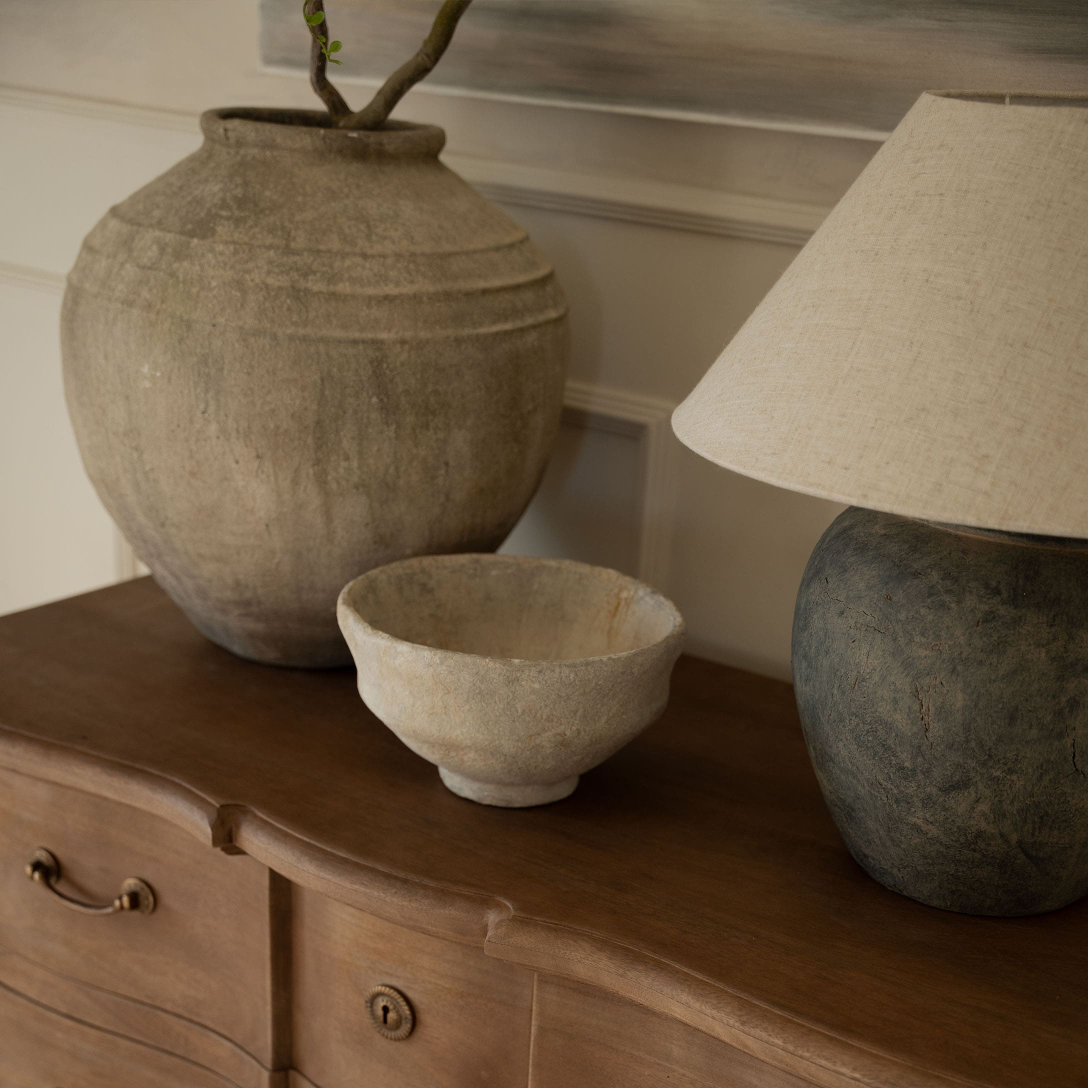 Vases et bol décoratifs en céramique aux tons naturels posés sur une commode en bois
