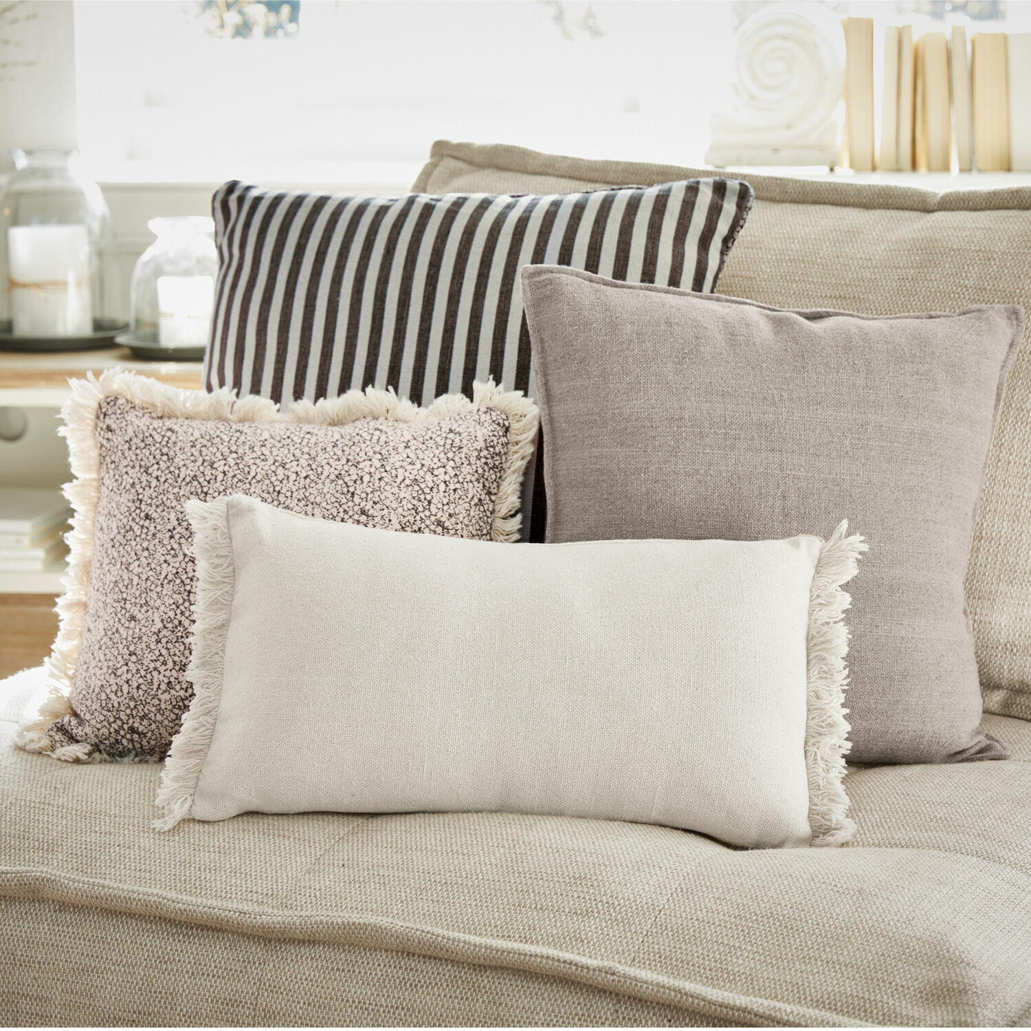 Lot de 4 coussins Valenciennes Ensemble de quatre coussins décoratifs aux tons neutres sur un canapé beige pour salon