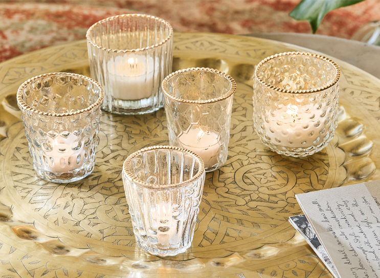 Ensemble de cinq photophores en verre avec bord doré sur un plateau décoratif en laiton