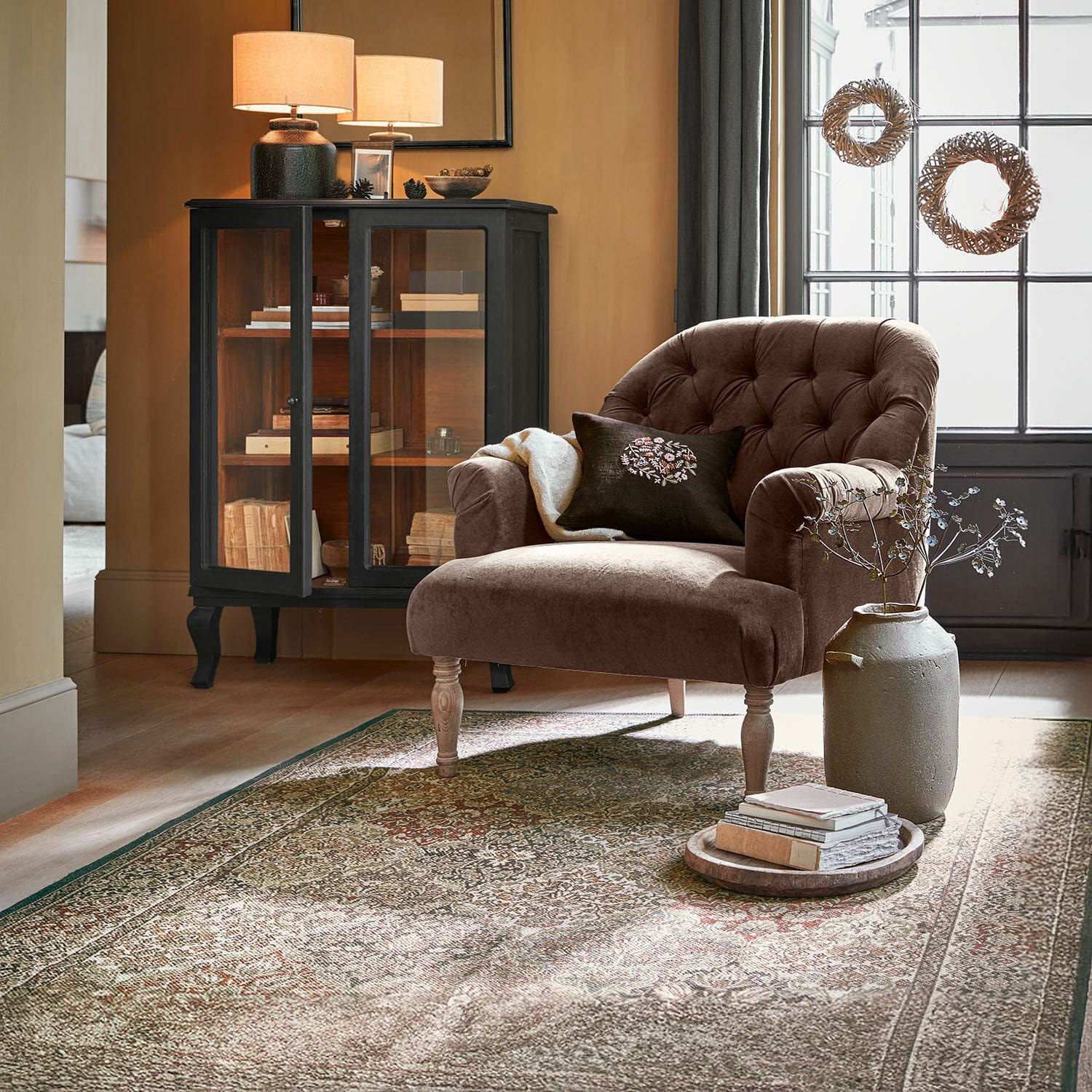 Tapis d'intérieur et d'extérieur Malhira Fauteuil en velours marron avec dossier capitonné et pieds en bois dans un salon chaleureux avec tapis