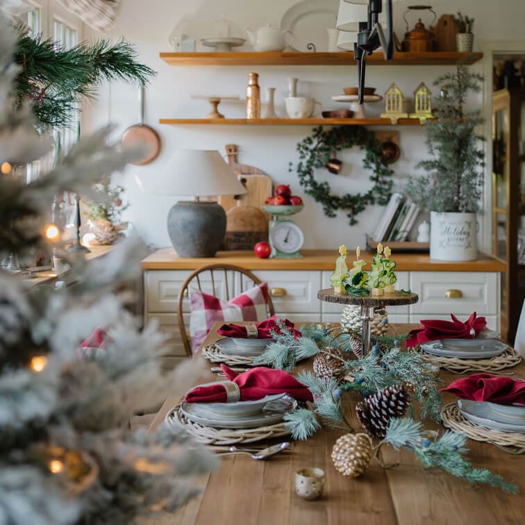 Table en bois décorée pour Noël avec serviettes rouges et décorations naturelles en pommes de pin et branches