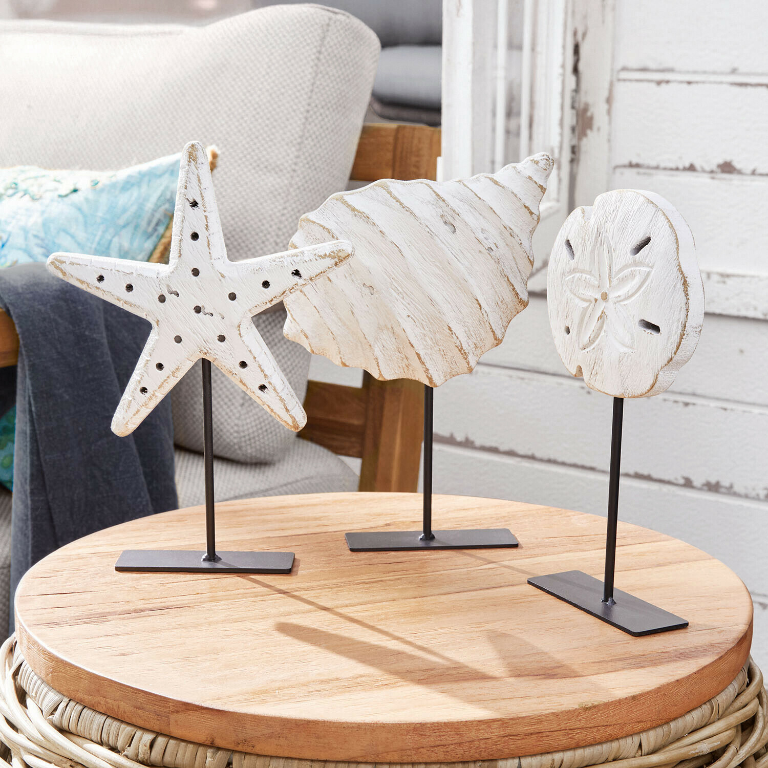 Décorations en bois blanc en forme de coquillages sur supports métalliques noirs posés sur une table en bois