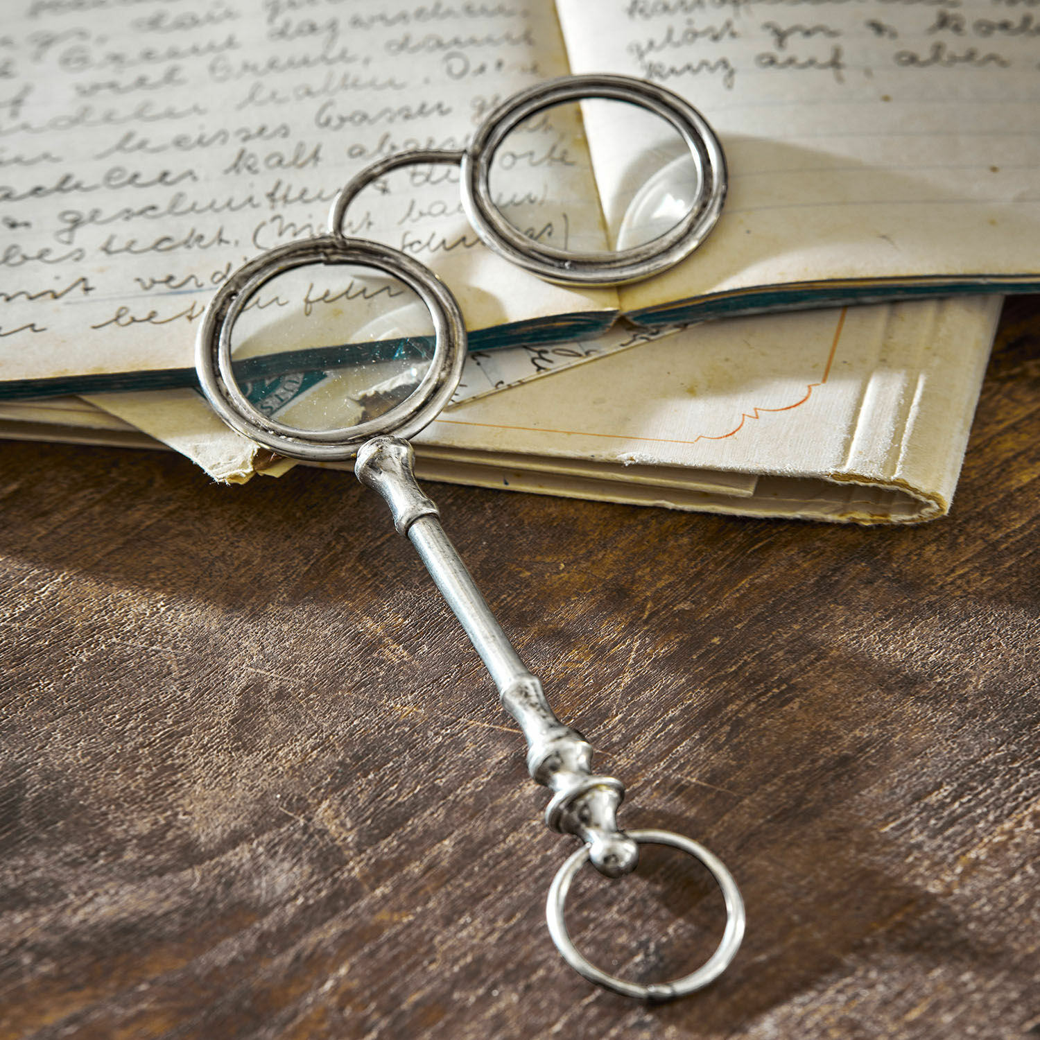 Lorgnon décoratif Loisy Loupe en métal avec deux lentilles rondes posée sur une table en bois près d'un livre ouvert