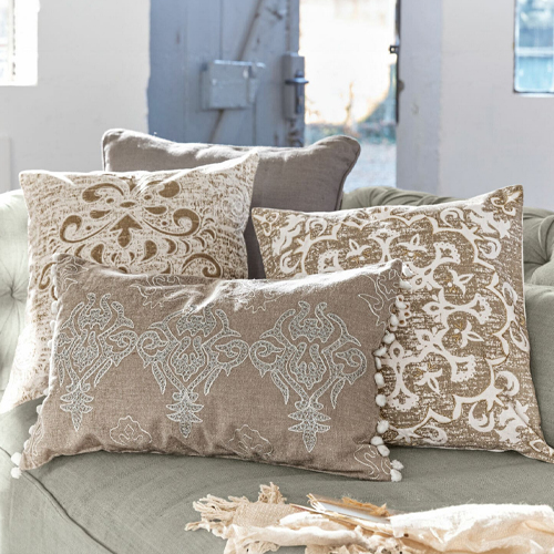 Ensemble de quatre coussins décoratifs beige et blanc avec motifs sur canapé, textile d'intérieur