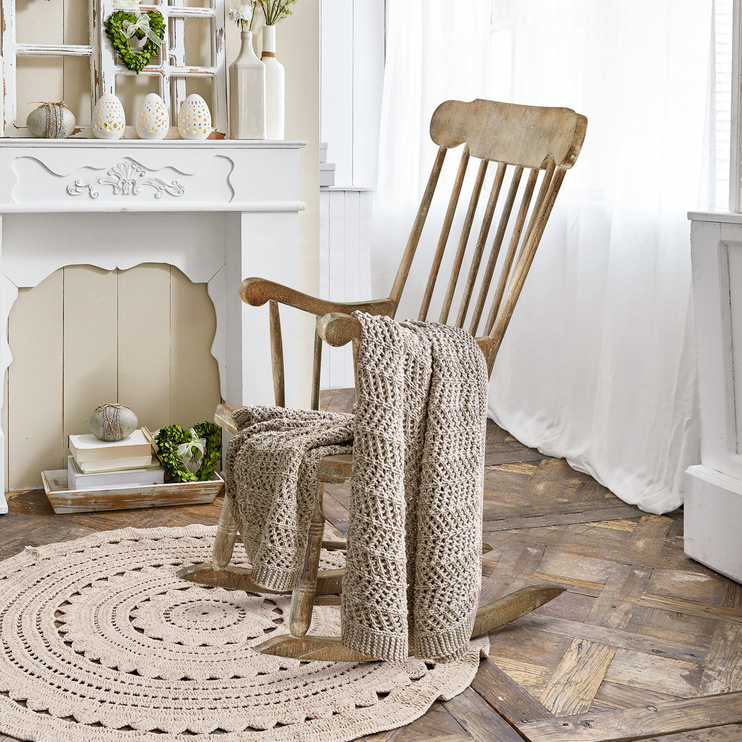 Fauteuil à bascule Adaleine Fauteuil à bascule en bois avec couverture beige tricotée sur tapis rond dans une pièce lumineuse