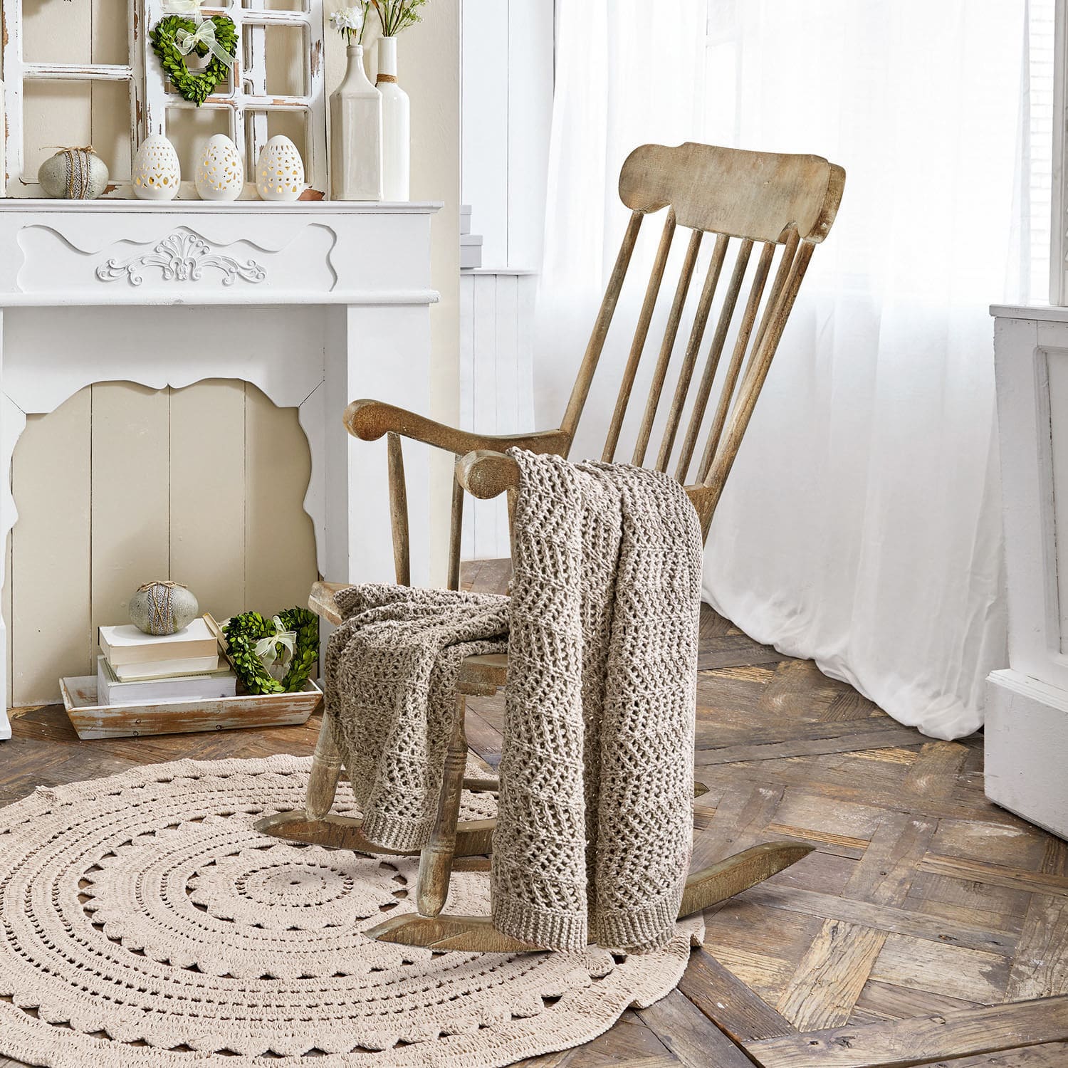 Fauteuil à bascule Adaleine Fauteuil à bascule en bois avec couverture beige tricotée sur tapis rond dans une pièce lumineuse