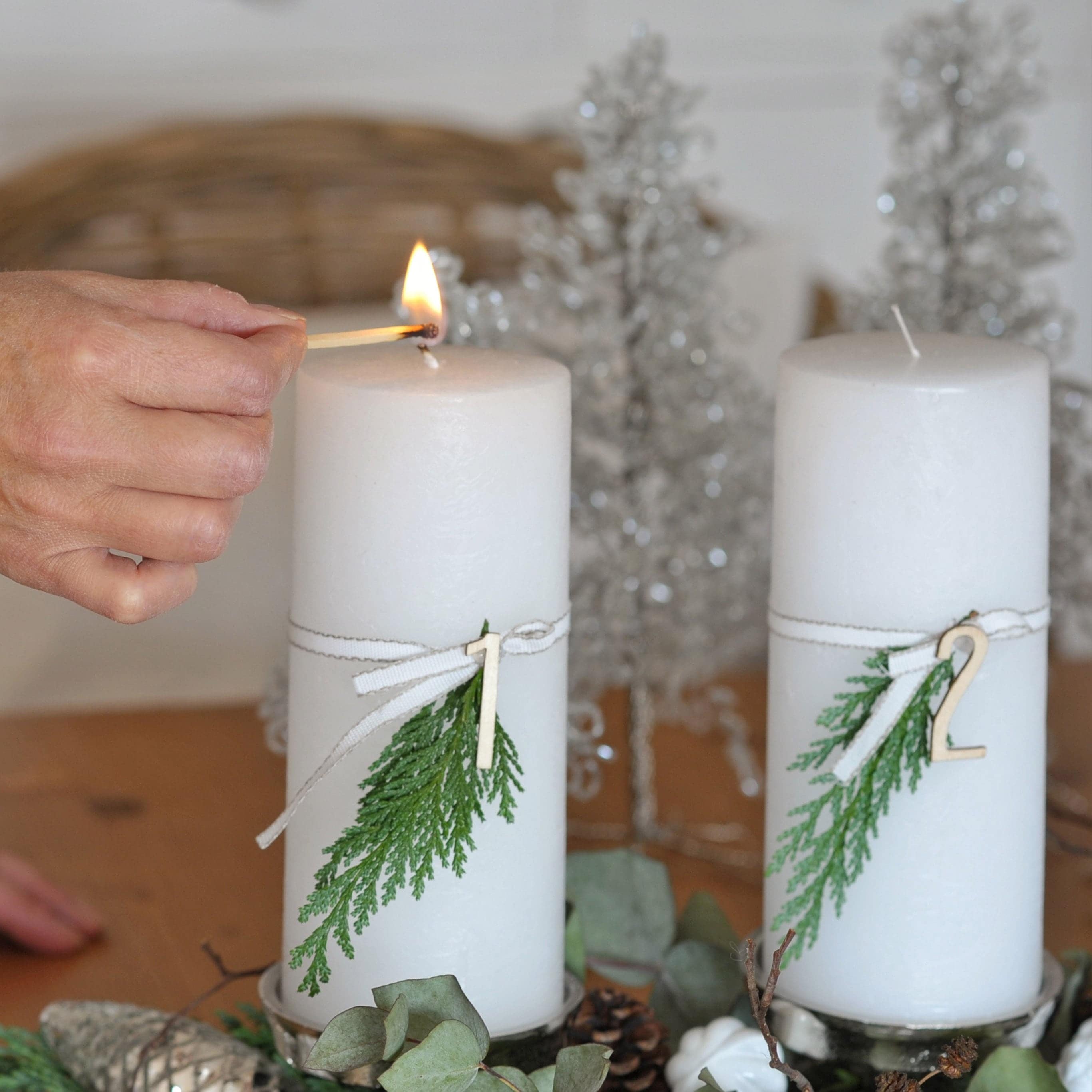 Bougies blanches d'Avent avec branches vertes et numéros en bois sur plateau décoratif de Noël