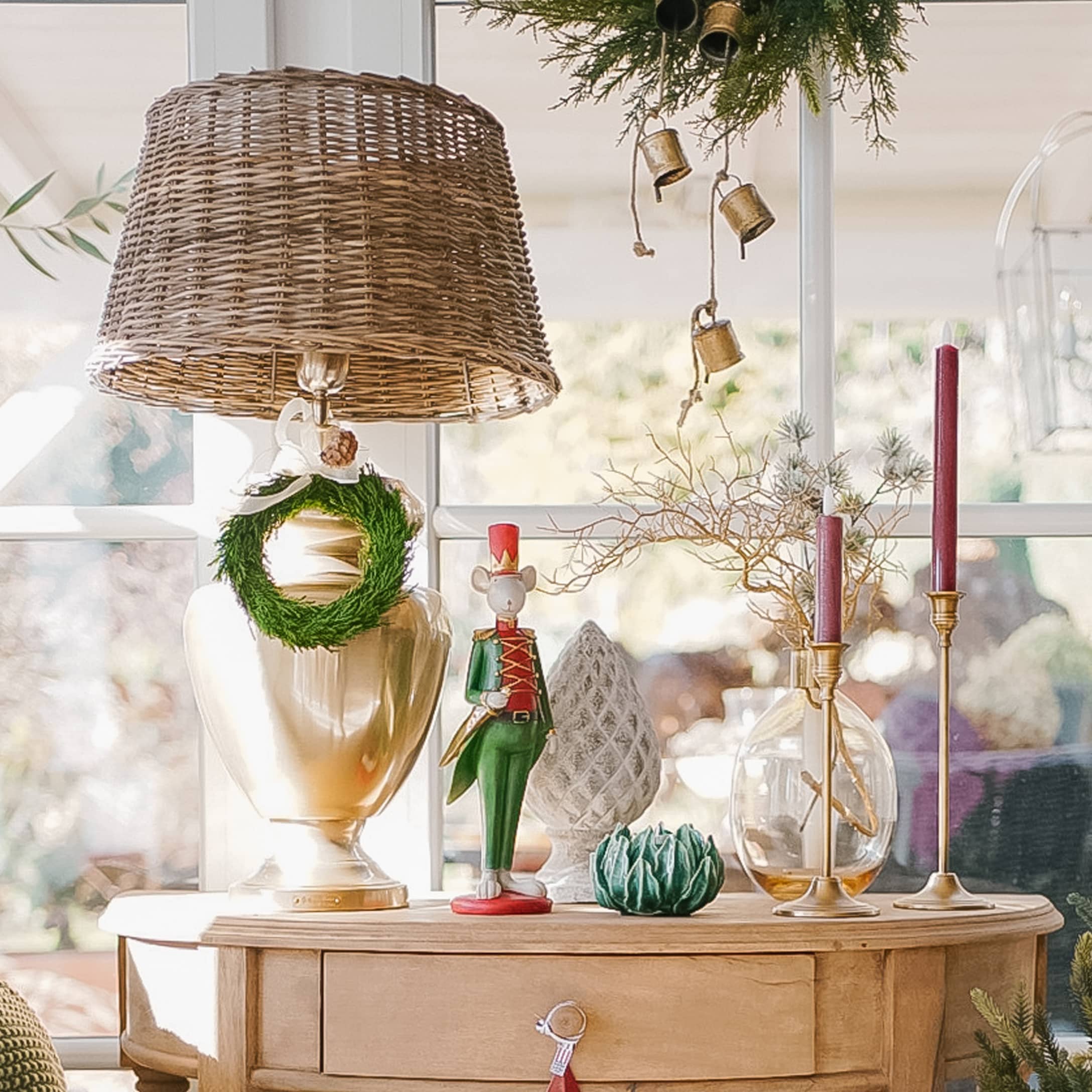 Lampe décorative avec abat-jour en osier et décorations de Noël sur une table en bois dans un intérieur lumineux