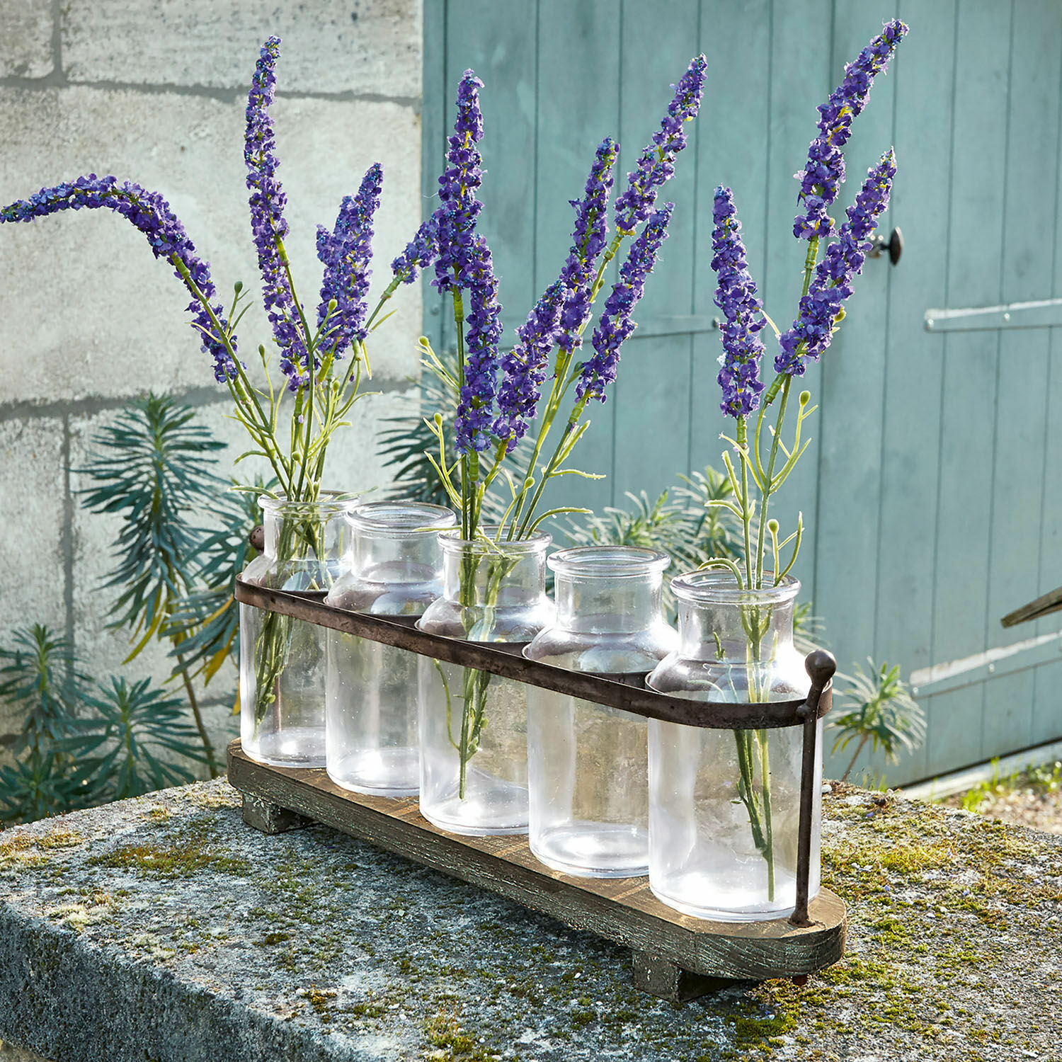 Lot de 5 vases Ranjo Ensemble de cinq vases en verre transparent avec support métallique sur base en bois, décoré de fleurs violettes