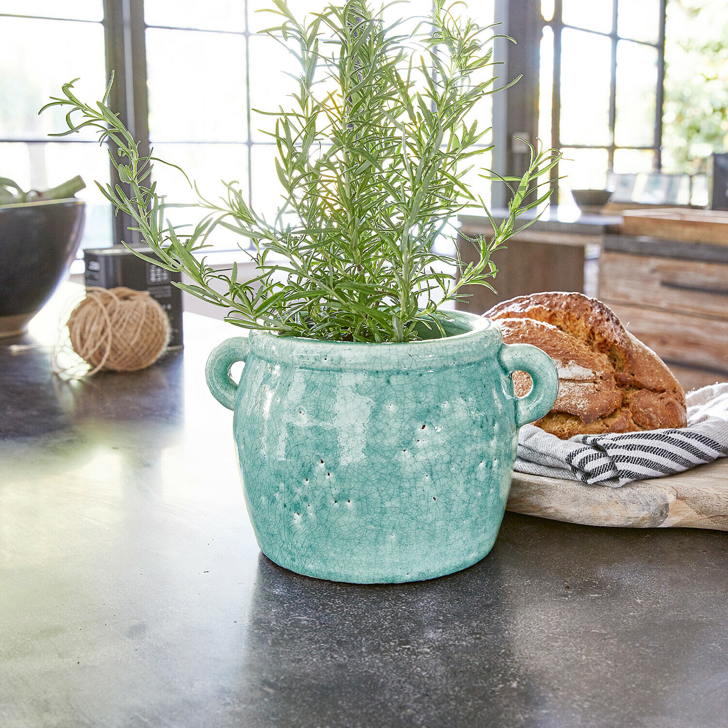Vase Elvin Pot en céramique turquoise avec poignées et plante verte sur plan de travail de cuisine avec pain