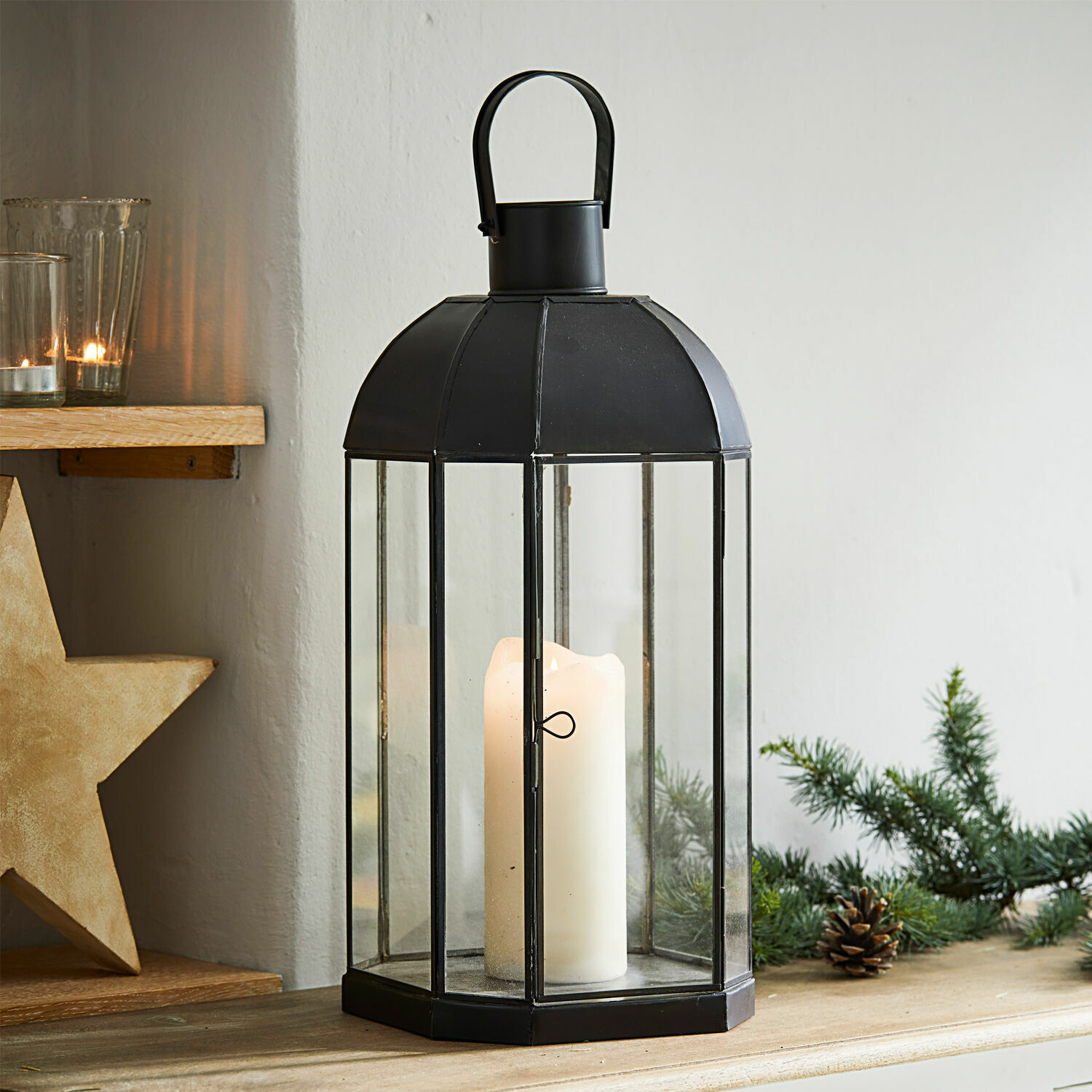 Lanterne Comines Lanterne noire en métal avec verre transparent et bougie blanche sur table en bois décorée pour Noël