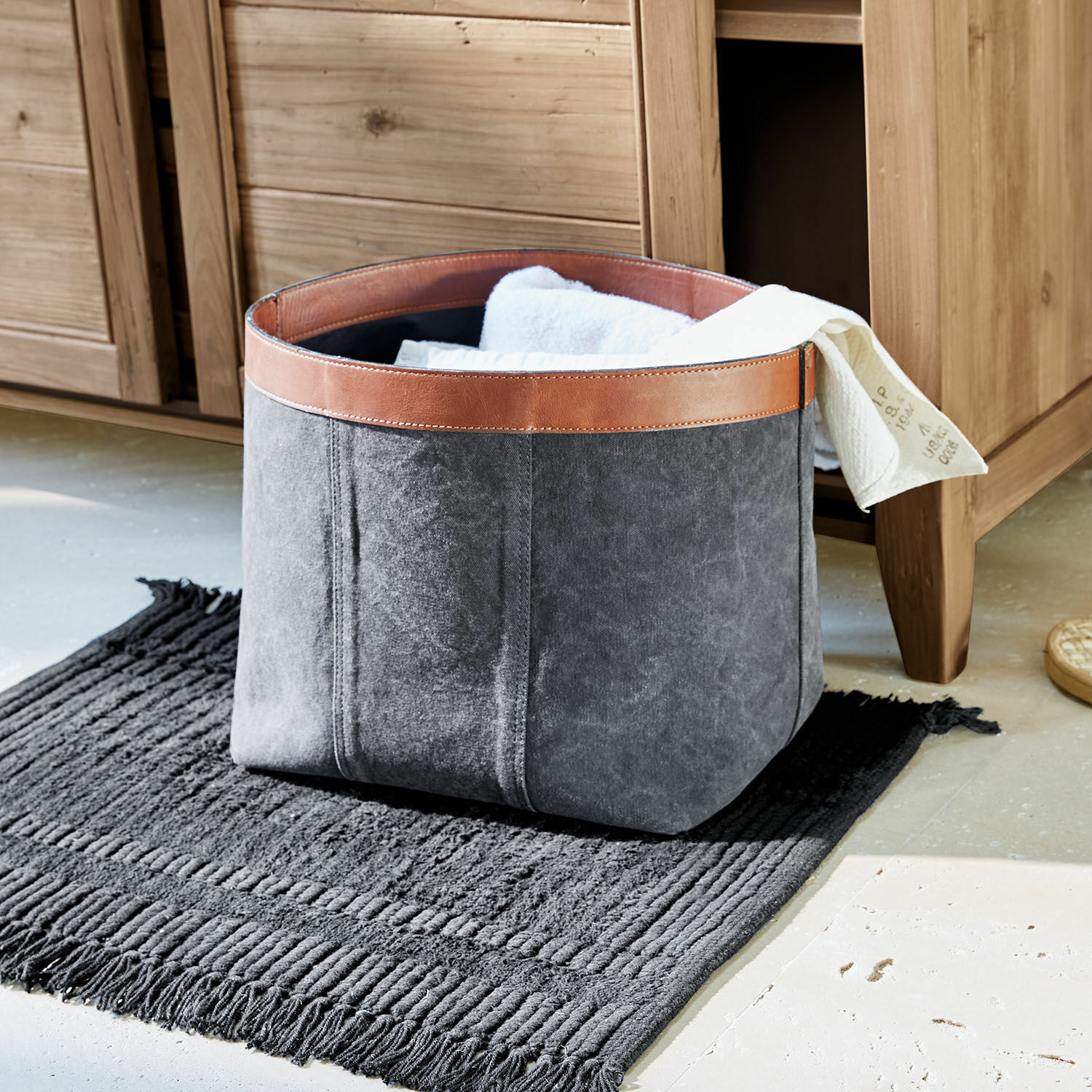 Corbeille Chansonet Panier gris en tissu avec bordure en cuir marron sur tapis noir pour rangement de linge