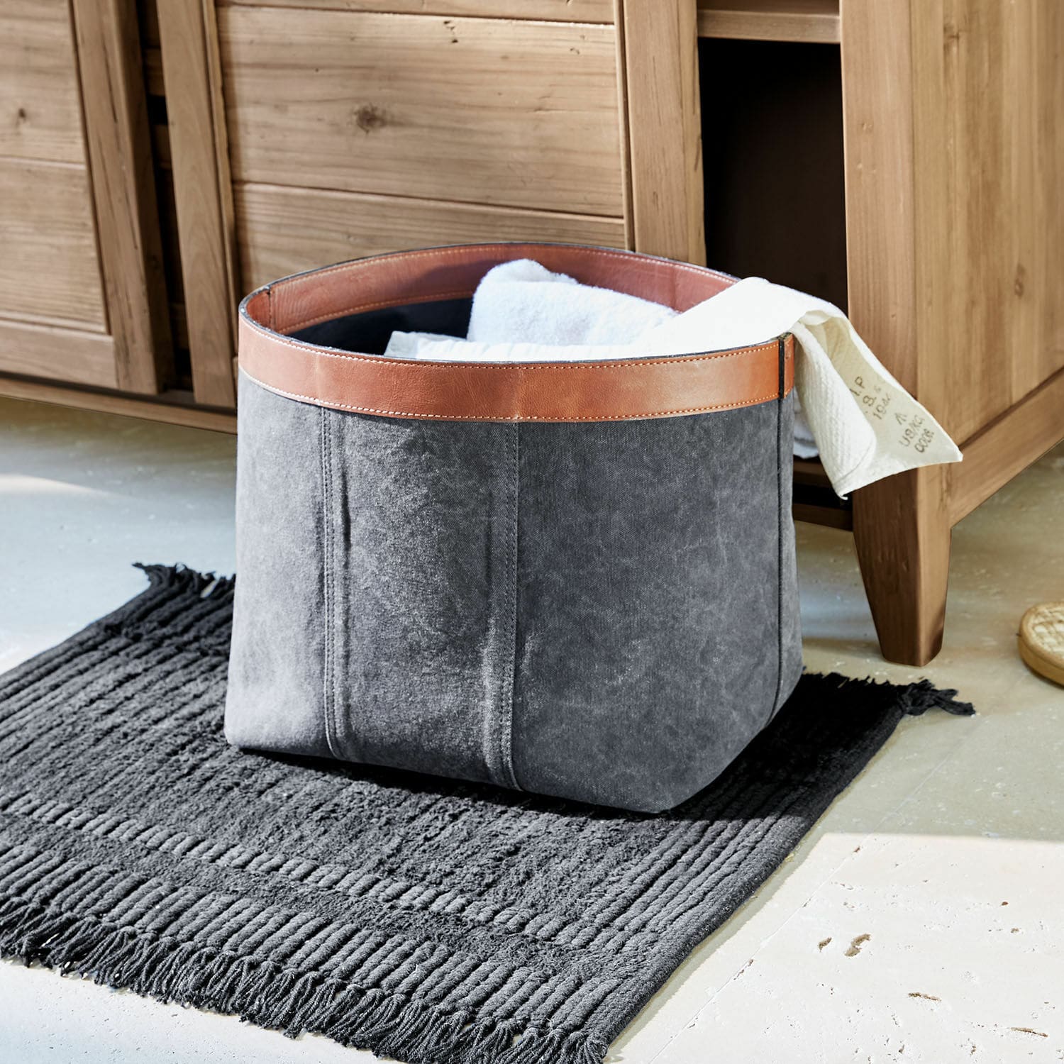 Corbeille Chansonet Panier gris en tissu avec bordure en cuir marron sur tapis noir pour rangement de linge