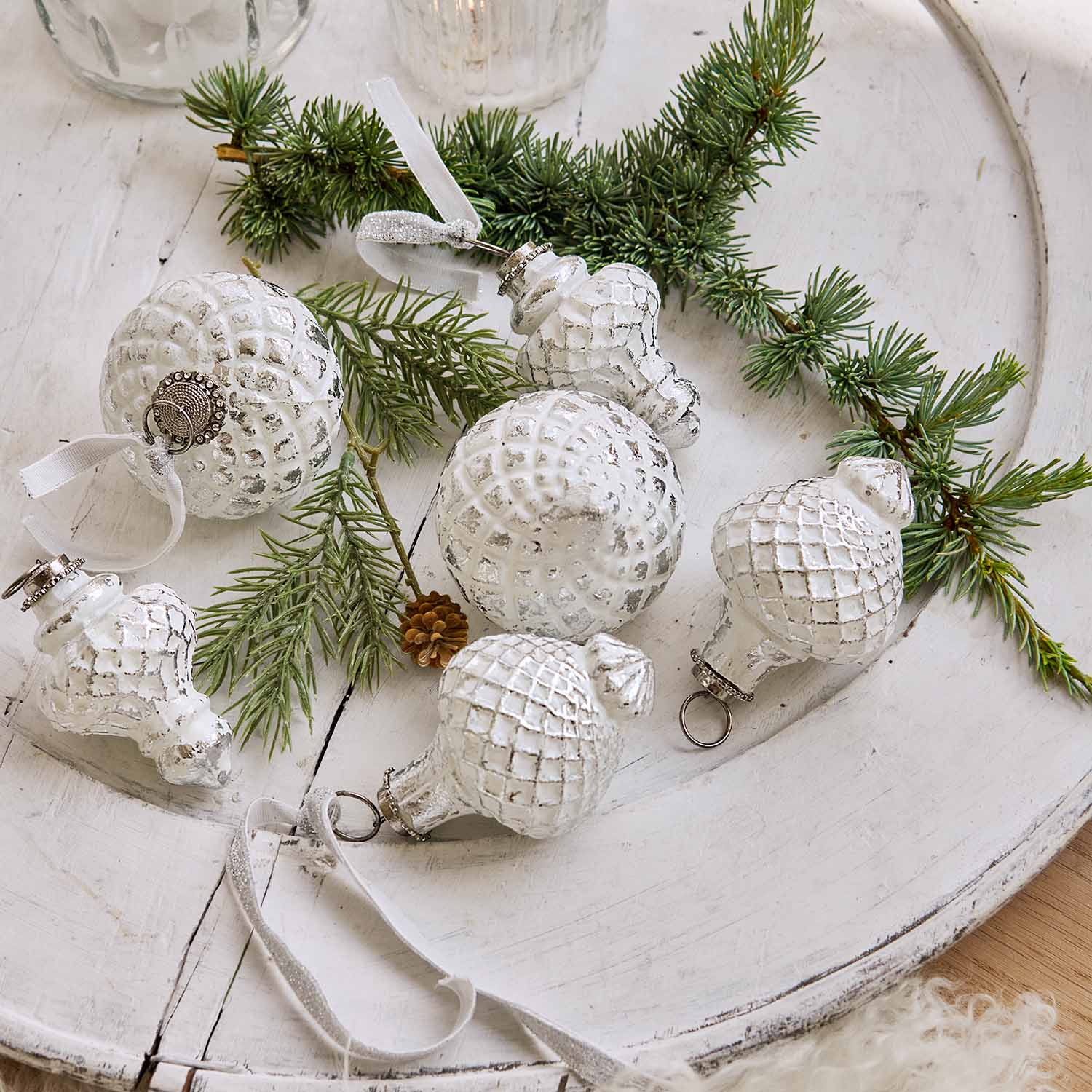 Décorations de Noël blanches à motif quadrillé sur plateau en bois avec branches de sapin, ambiance festive