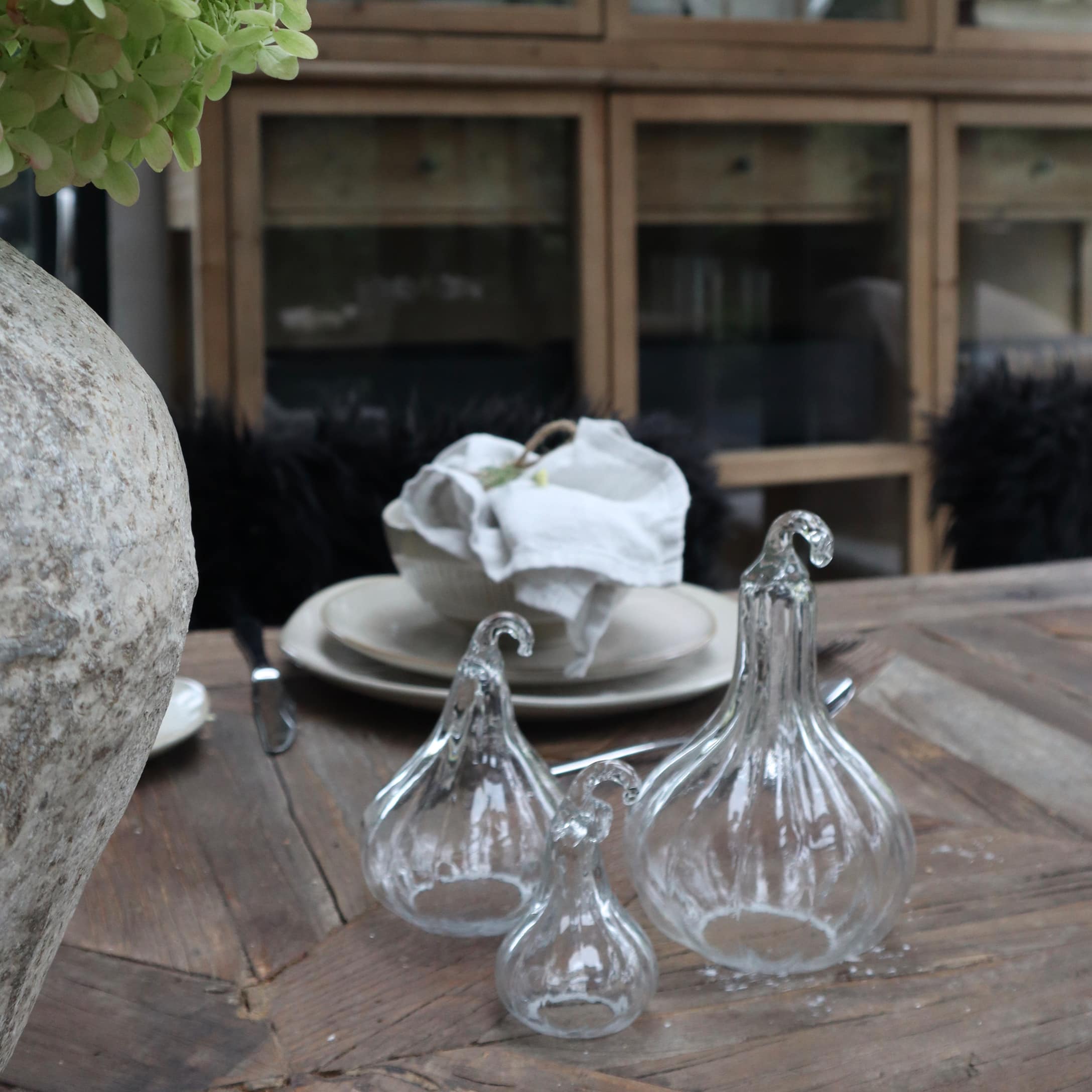 Décorations en verre transparent en forme de citrouille sur une table en bois dans un intérieur rustique