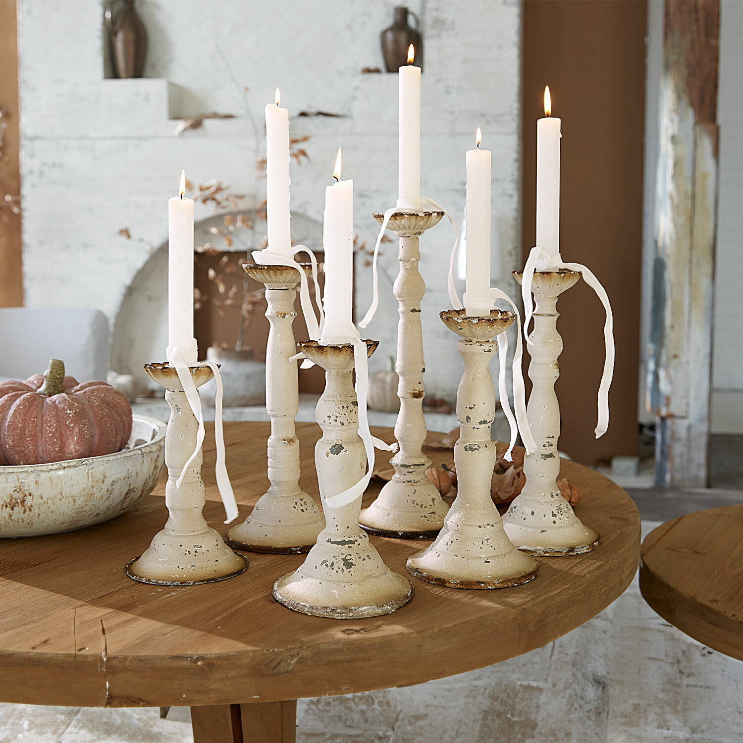 Lot de 6 bougeoirs Rivondelle Ensemble de sept bougeoirs en métal crème avec bougies blanches sur une table en bois, décoration intérieure