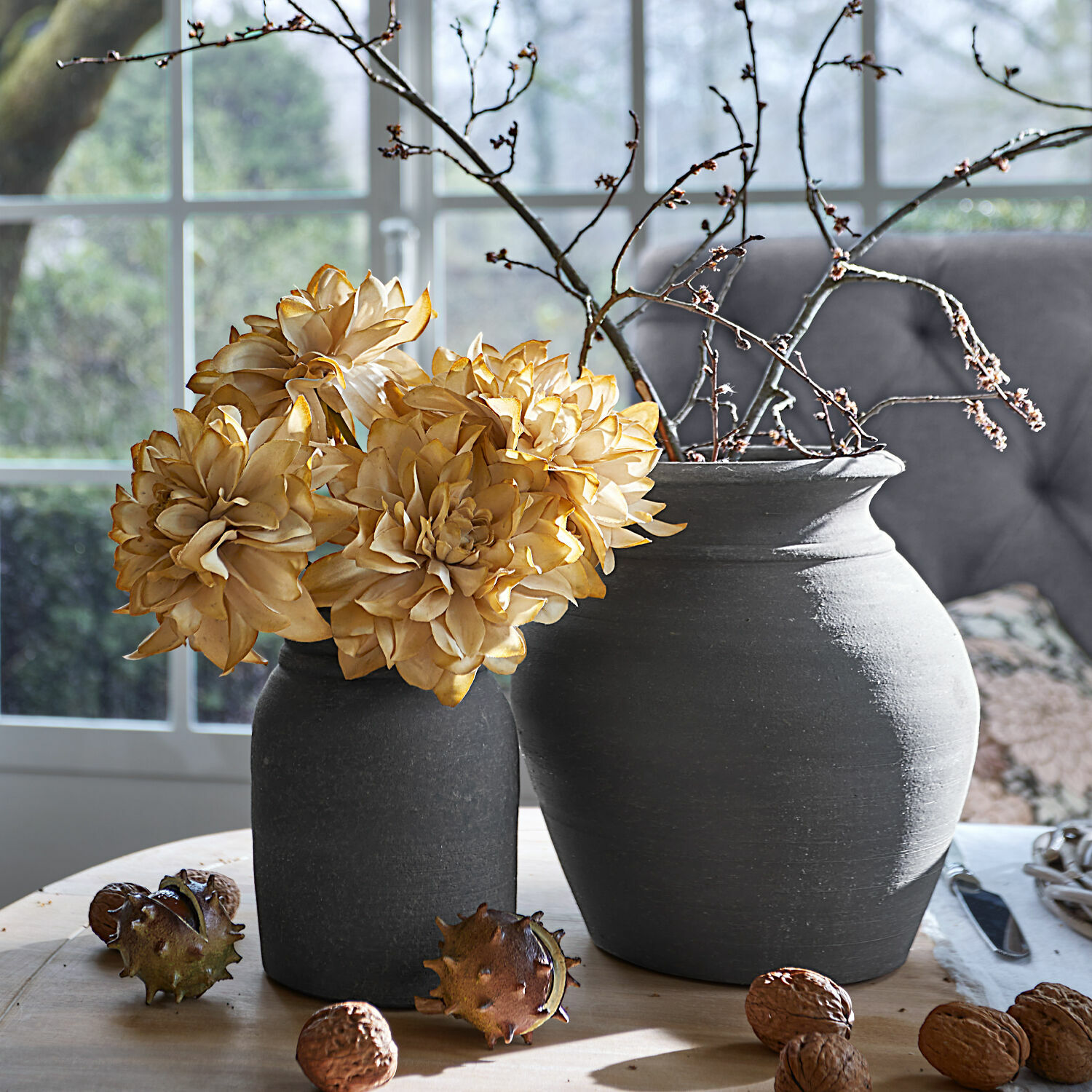 Lot de 2 vases Molduc Deux vases en céramique grise avec fleurs séchées et branches sur une table en bois avec des noix