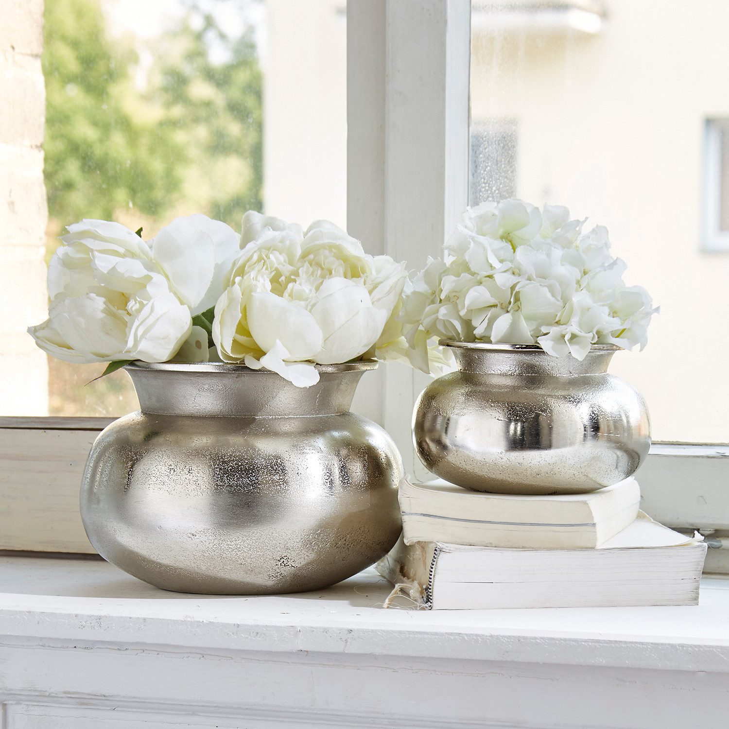 Lot de 2 vases Clément Deux vases en métal argenté avec fleurs blanches sur rebord de fenêtre, décoration intérieure vintage