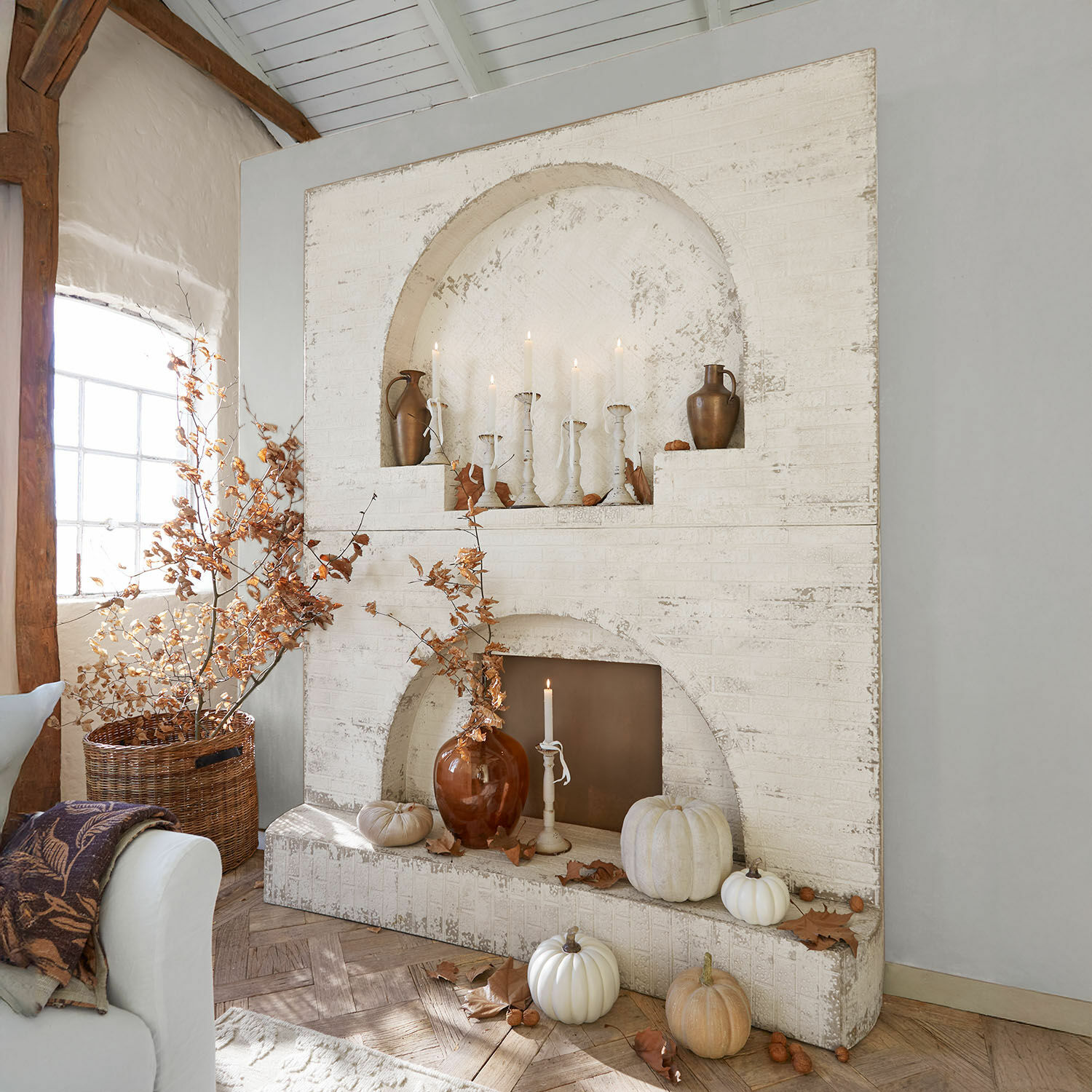 Console de cheminée Forêt Émeraude Cheminée blanche en brique décorée avec des citrouilles et des bougies dans un intérieur rustique