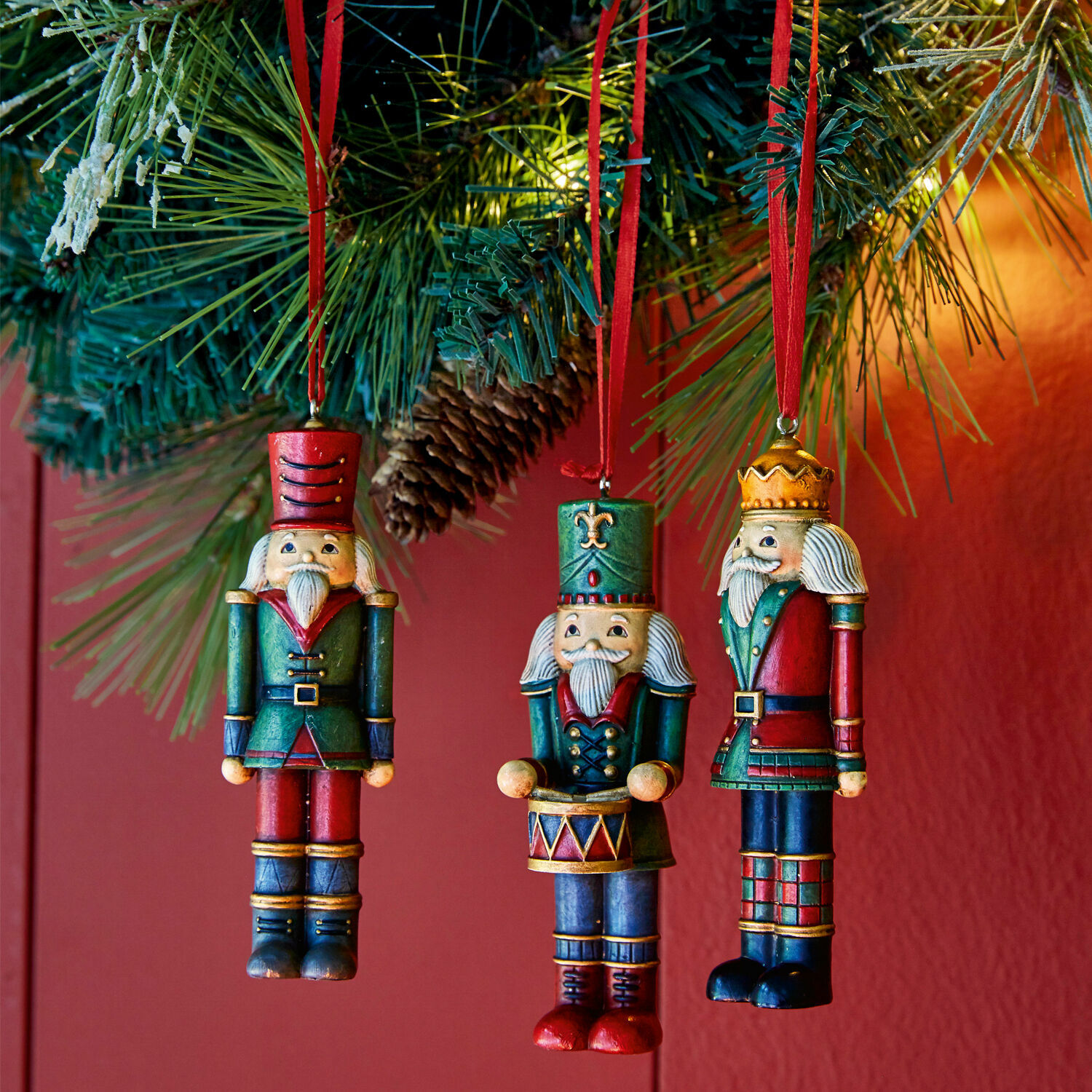 Lot de 3 décorations à suspendre Laudat Trois décorations de Noël en bois en forme de soldats rouges et verts suspendues à une branche de sapin