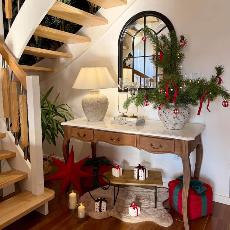 Console en bois avec plateau en marbre, lampe et décoration de Noël avec branches vertes et ornements rouges