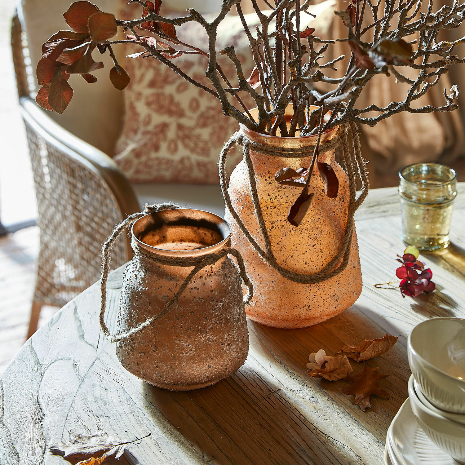Lot de 2 vases Querello Deux vases décoratifs en verre mat orange avec cordes sur une table en bois dans un salon lumineux