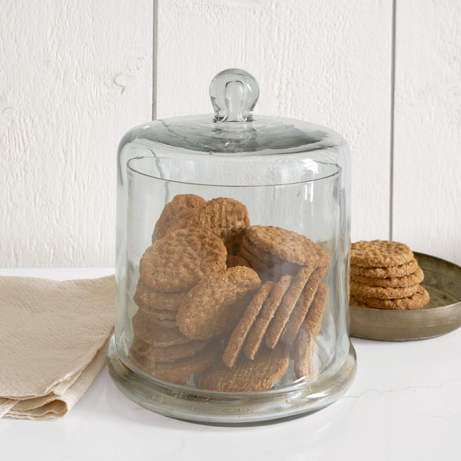 Cloche en verre Aislora Cloche en verre transparent remplie de savons crème sur fond blanc, ambiance salle de bain