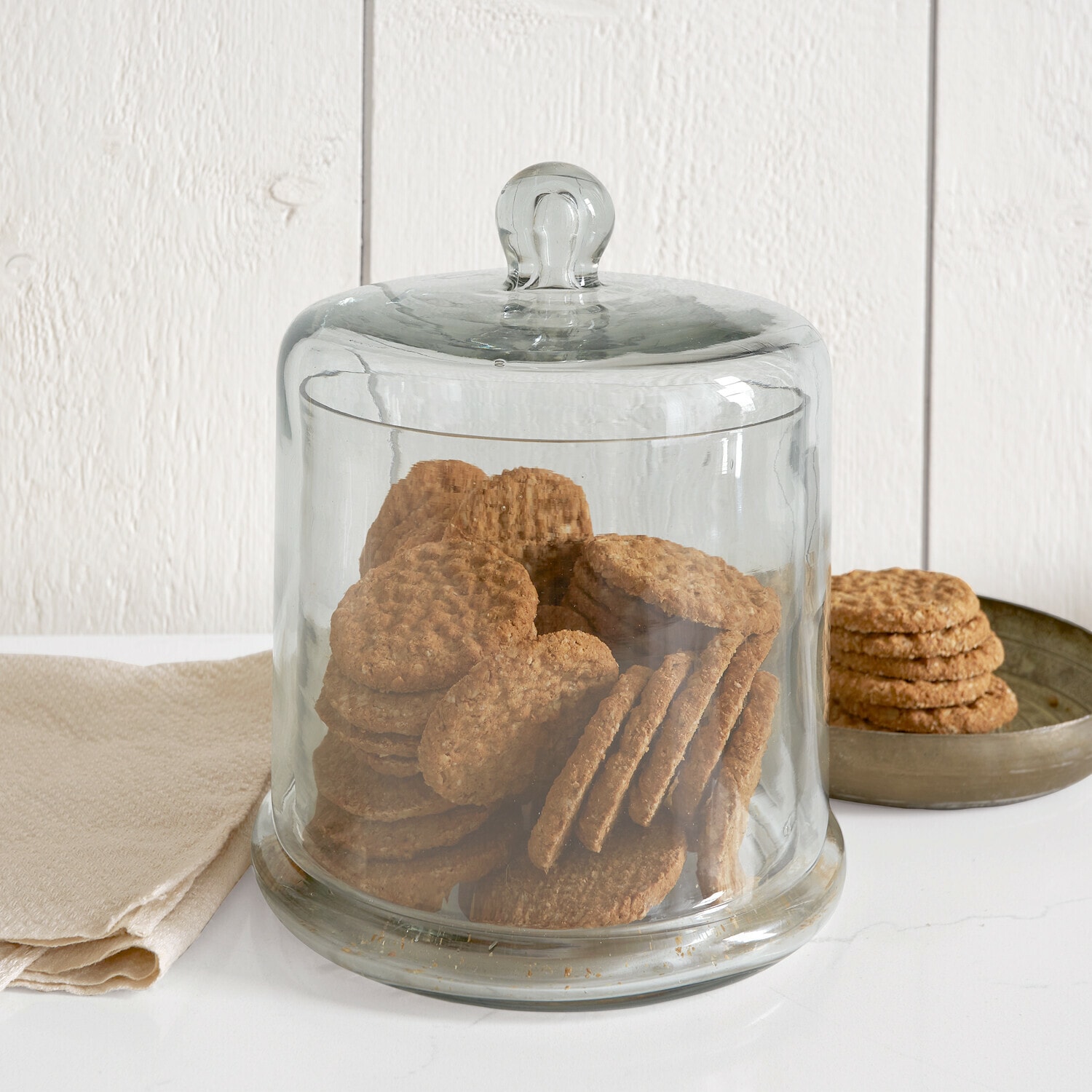 Cloche en verre Aislora Cloche en verre transparent remplie de savons crème sur fond blanc, ambiance salle de bain
