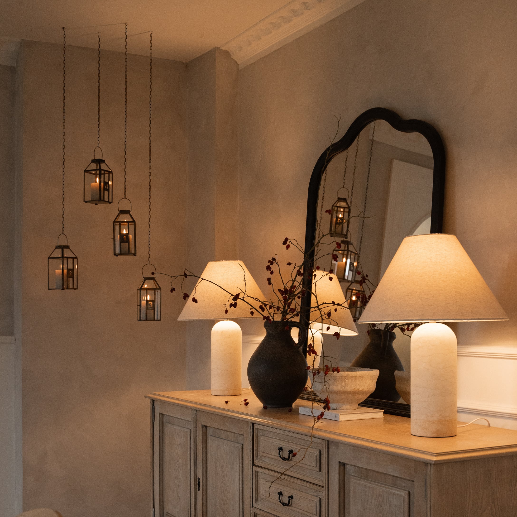 Couronne de l'Avent décorative avec quatre bougies dans des lanternes en verre suspendues dans un intérieur chaleureux
