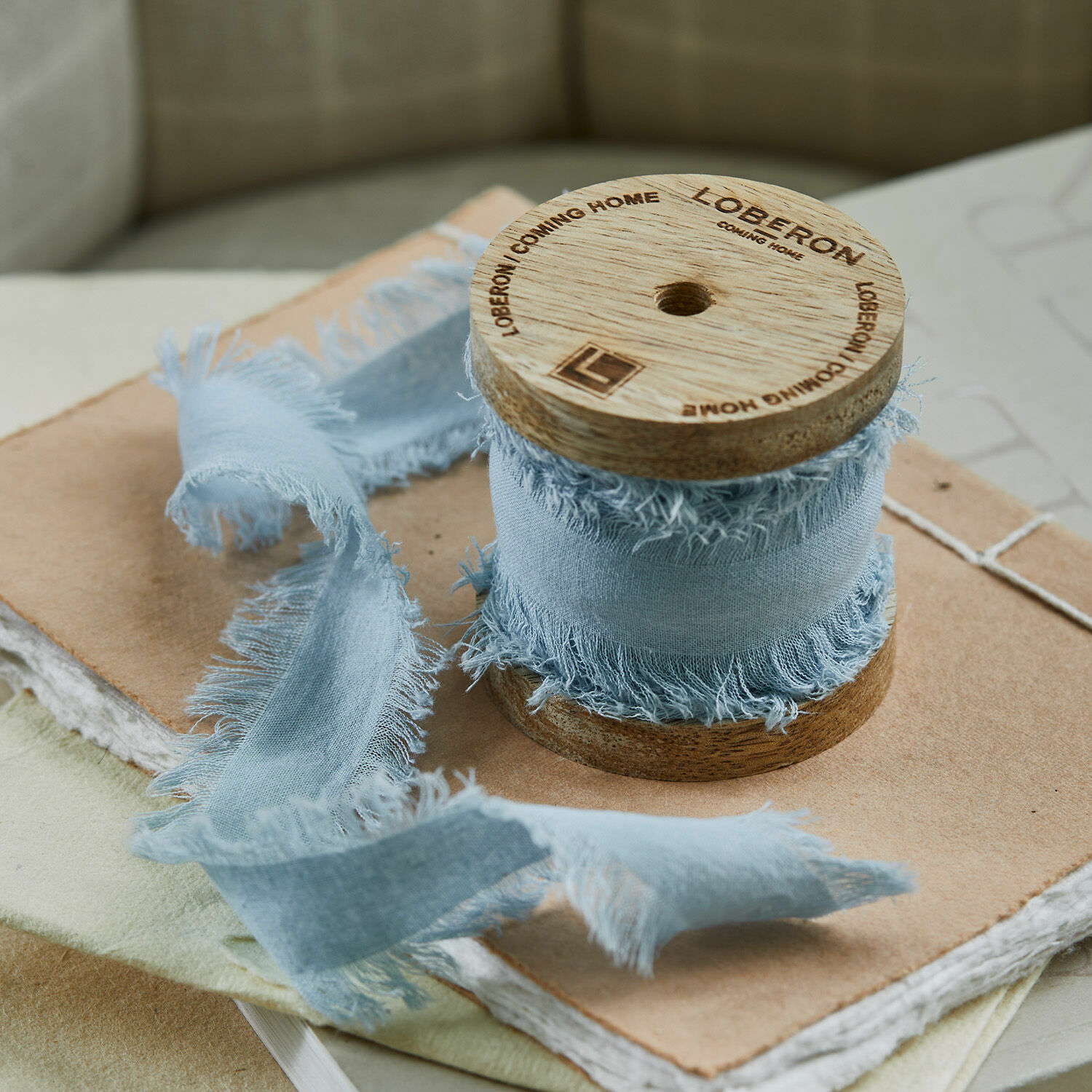 Ruban Celoria Ruban bleu en coton à bords effilochés enroulé sur une bobine en bois sur des carnets