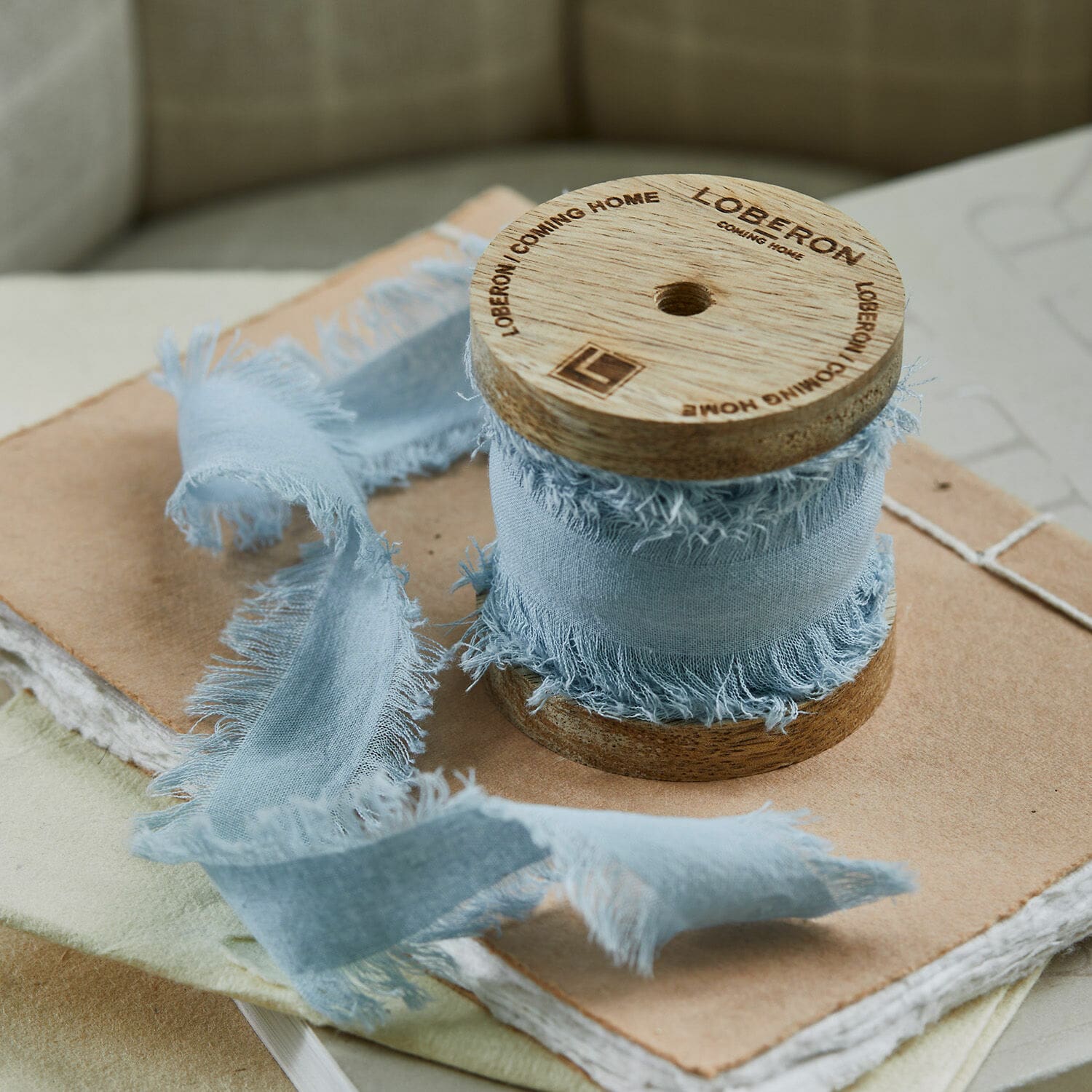 Ruban Celoria Ruban bleu en coton à bords effilochés enroulé sur une bobine en bois sur des carnets