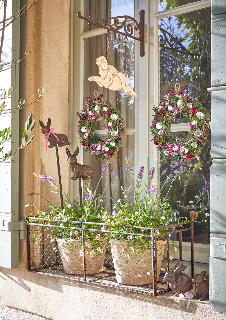 Décoration de fenêtre avec support en métal, pots de fleurs et couronnes printanières avec œufs et lapins