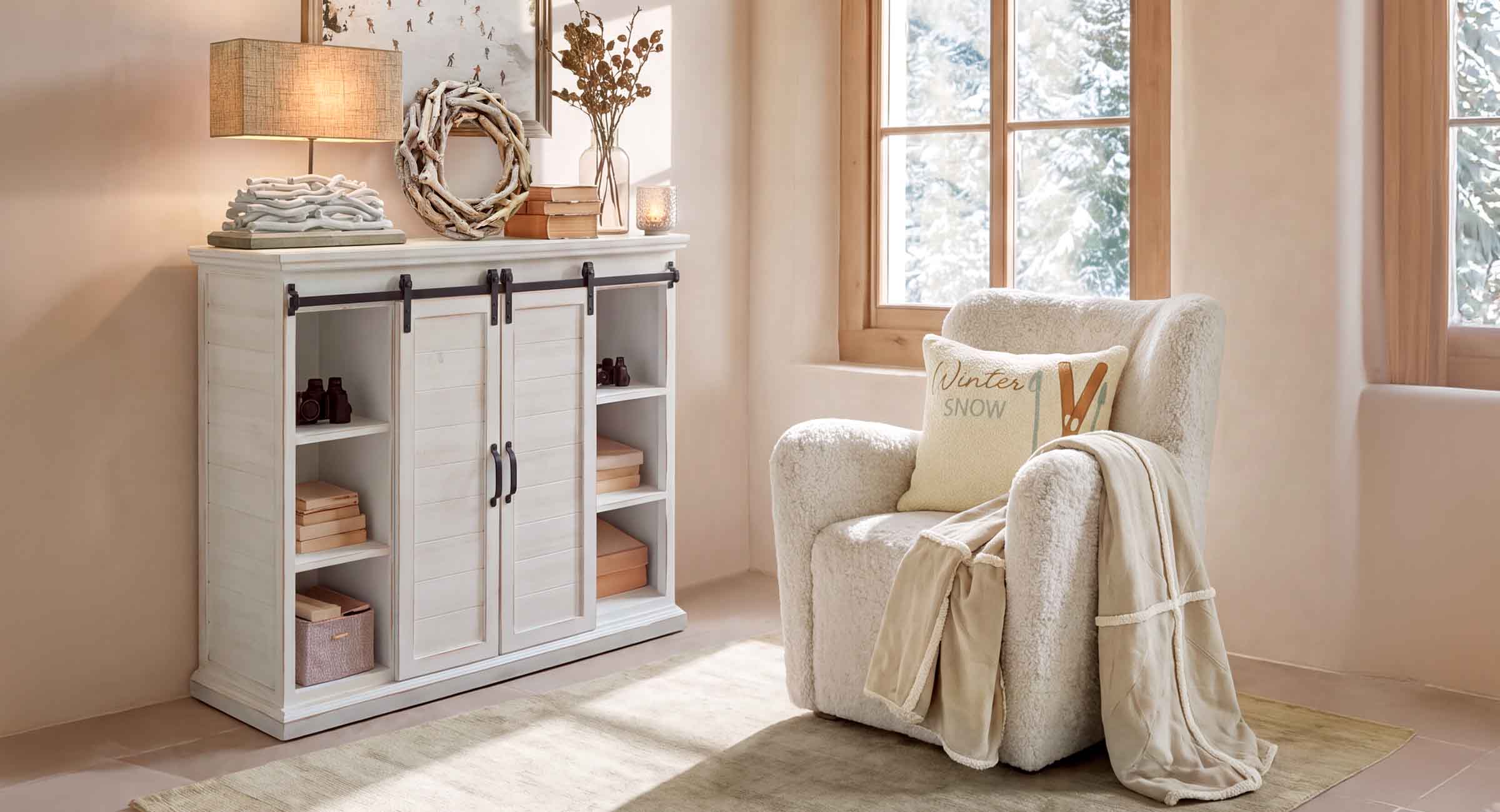 Coin cosy avec fauteuil blanc en tissu pelucheux et buffet en bois clair dans une pièce lumineuse avec vue hivernale