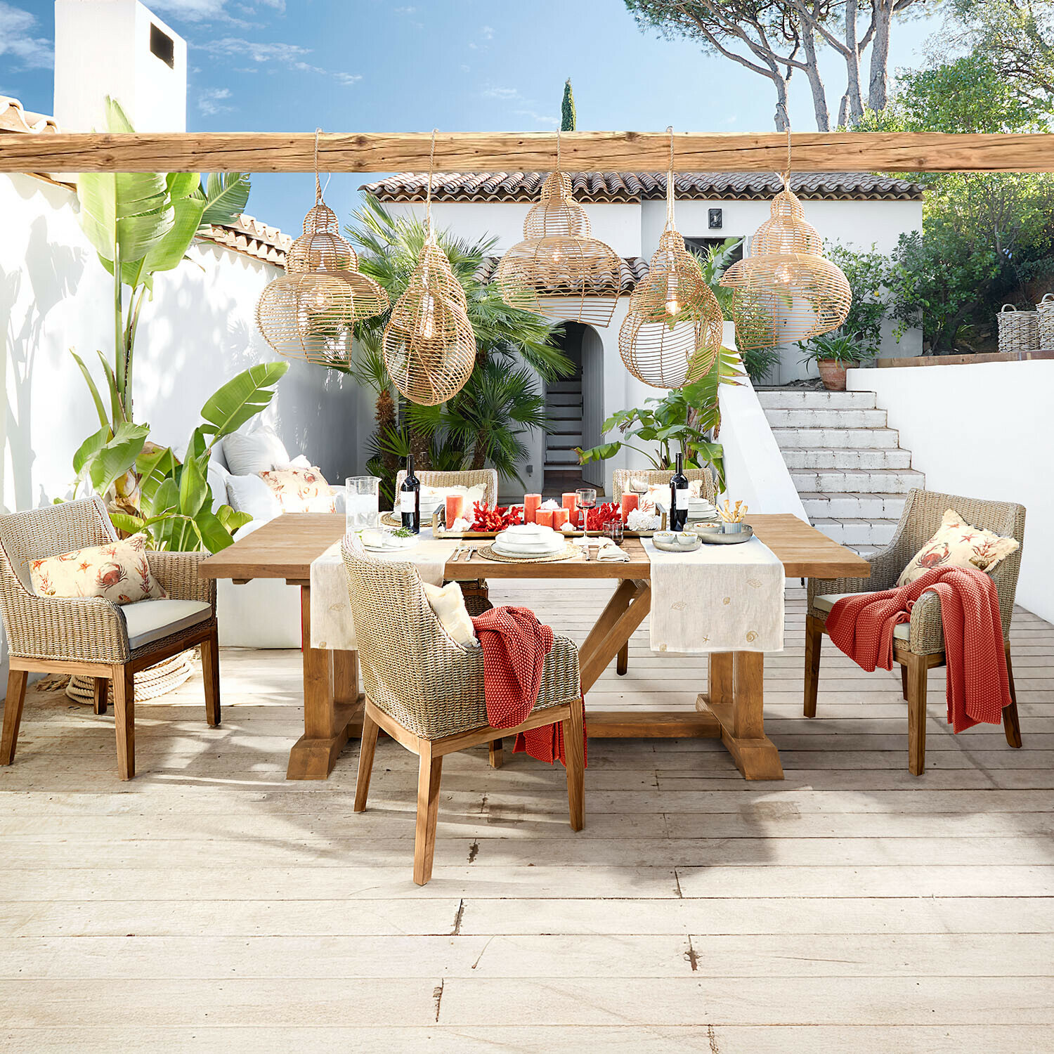 Table Melvoro Ensemble de mobilier de jardin en bois et rotin naturel avec suspensions en osier dans un patio lumineux