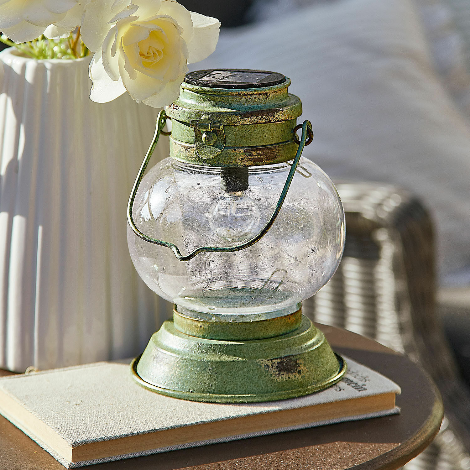 Lanterne solaire Nivalea Lanterne en métal vert avec globe en verre transparent posée sur un livre, décoration intérieure